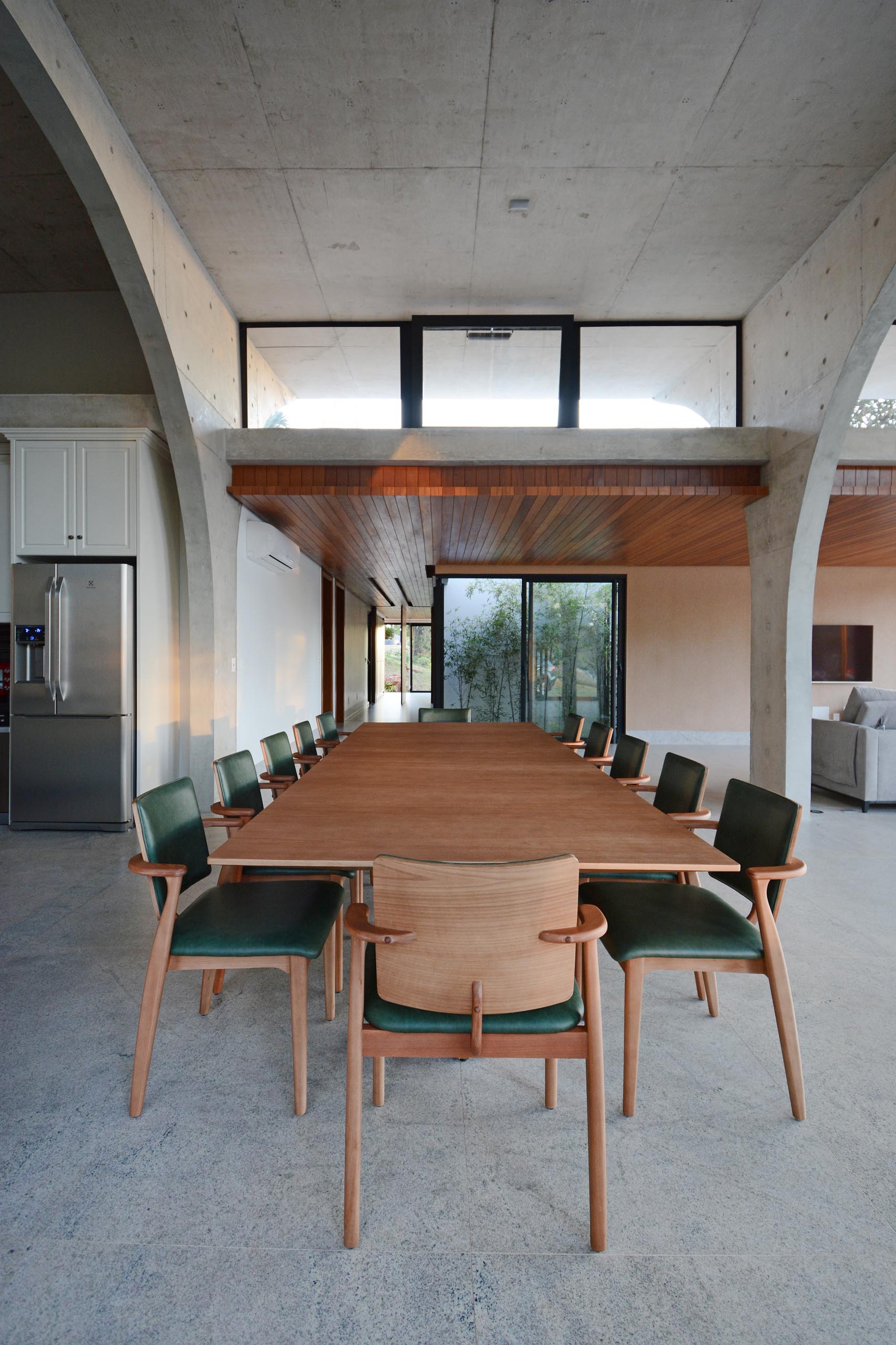 A pivoting front door welcomes people to the home, while a wood ceiling with lighting adds a sense of warmth to the interior.