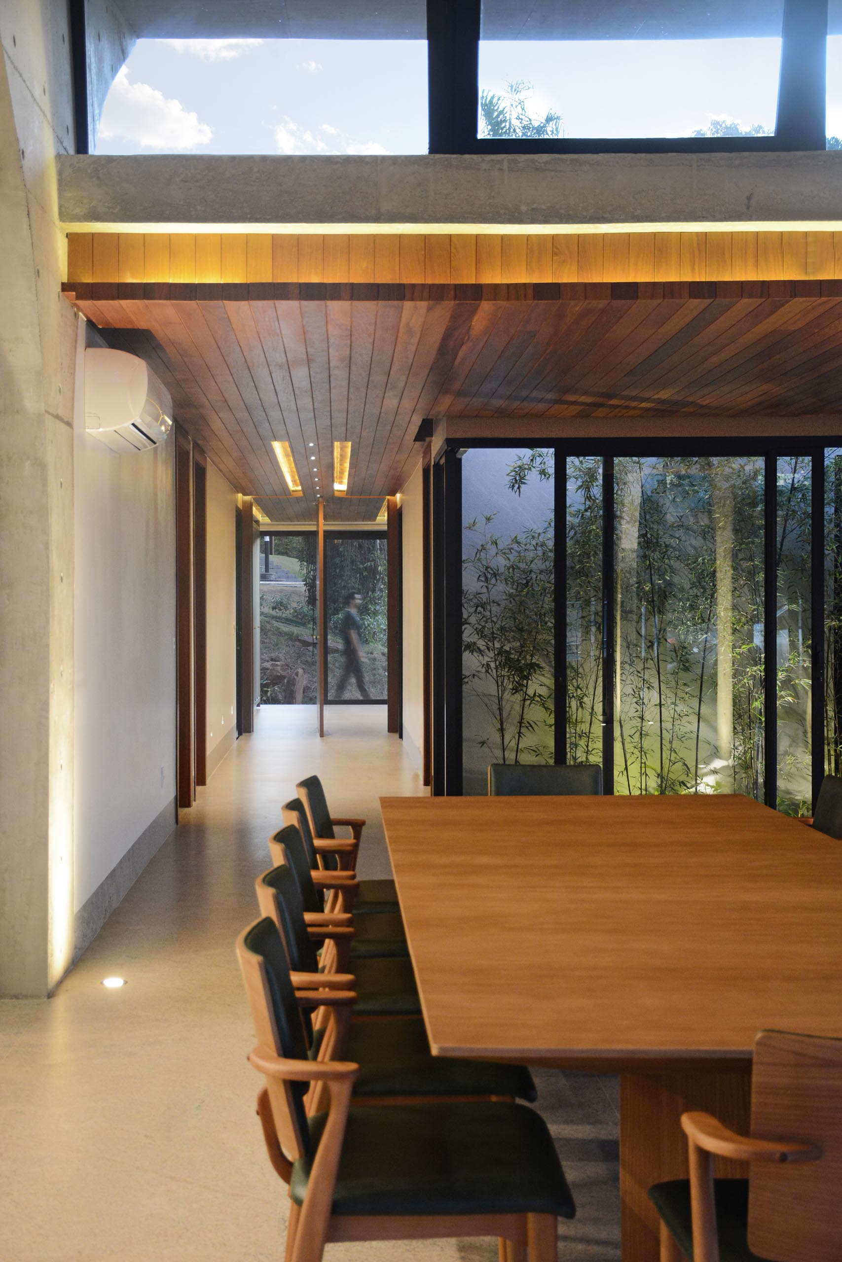 A pivoting front door welcomes people to the home, while a wood ceiling with lighting adds a sense of warmth to the interior.