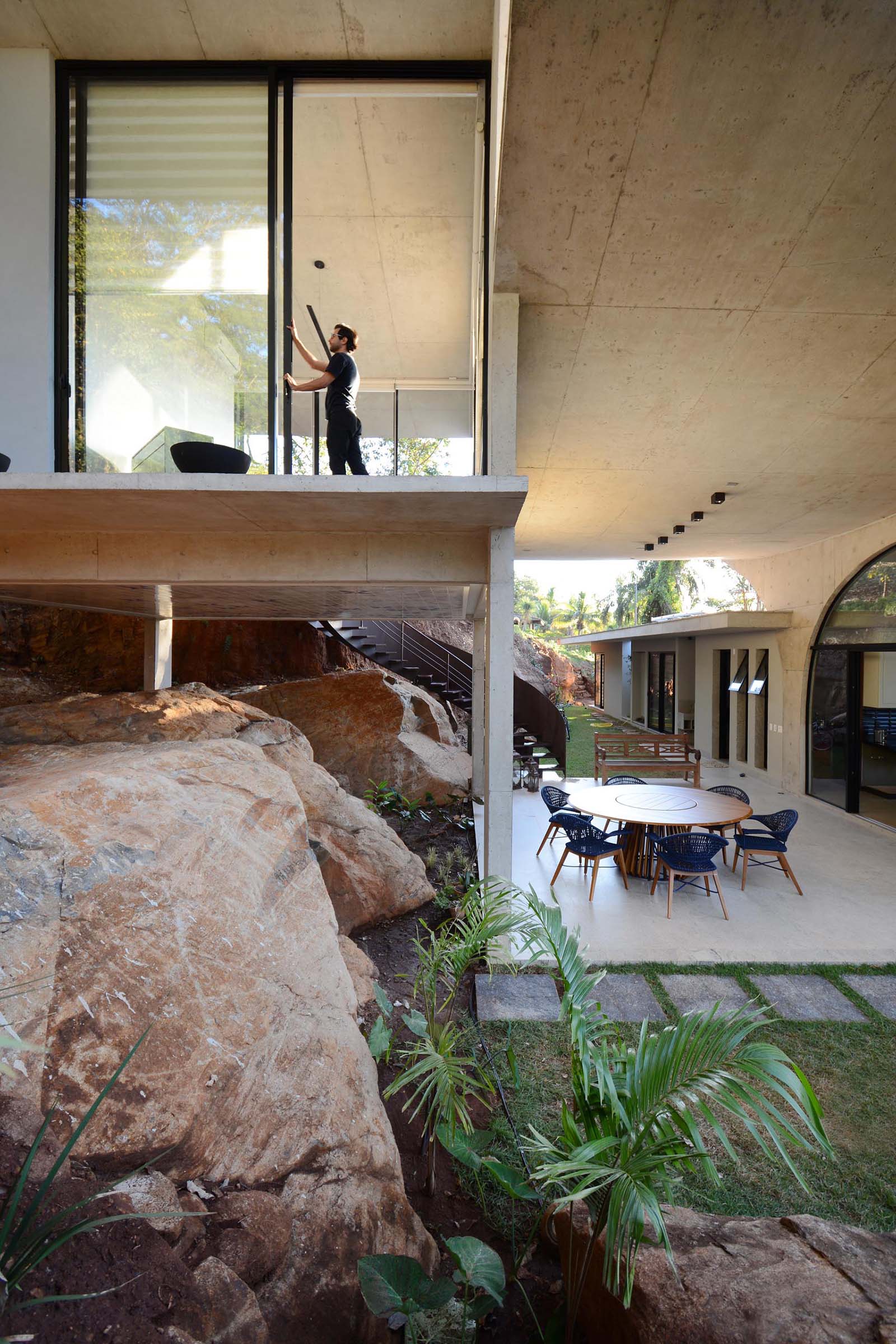 A modern concrete home with oversized sliding glass doors and a covered outdoor patio.