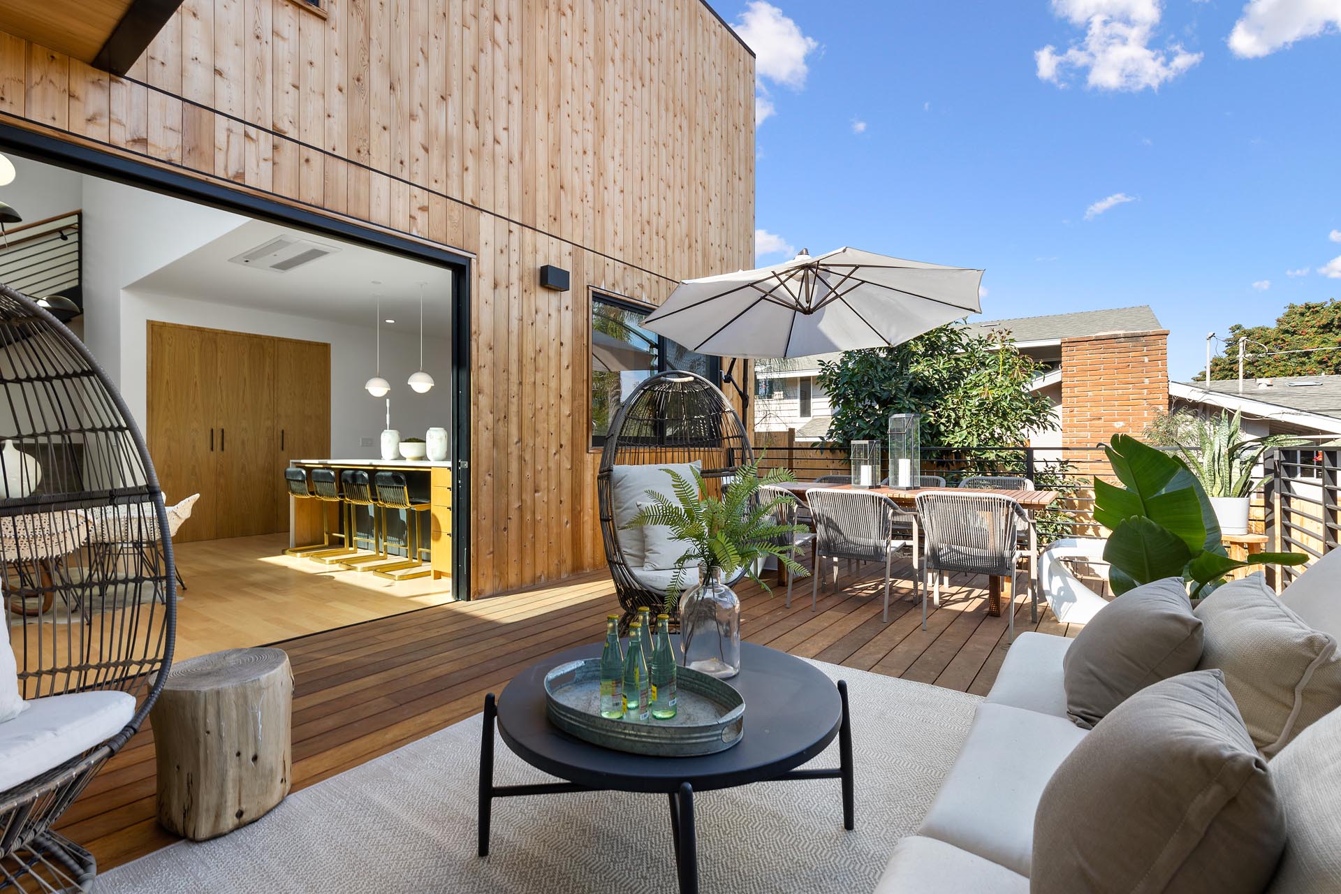 Sliding doors open up the interior of this modern home to a deck that's furnished for outdoor dining and lounging.