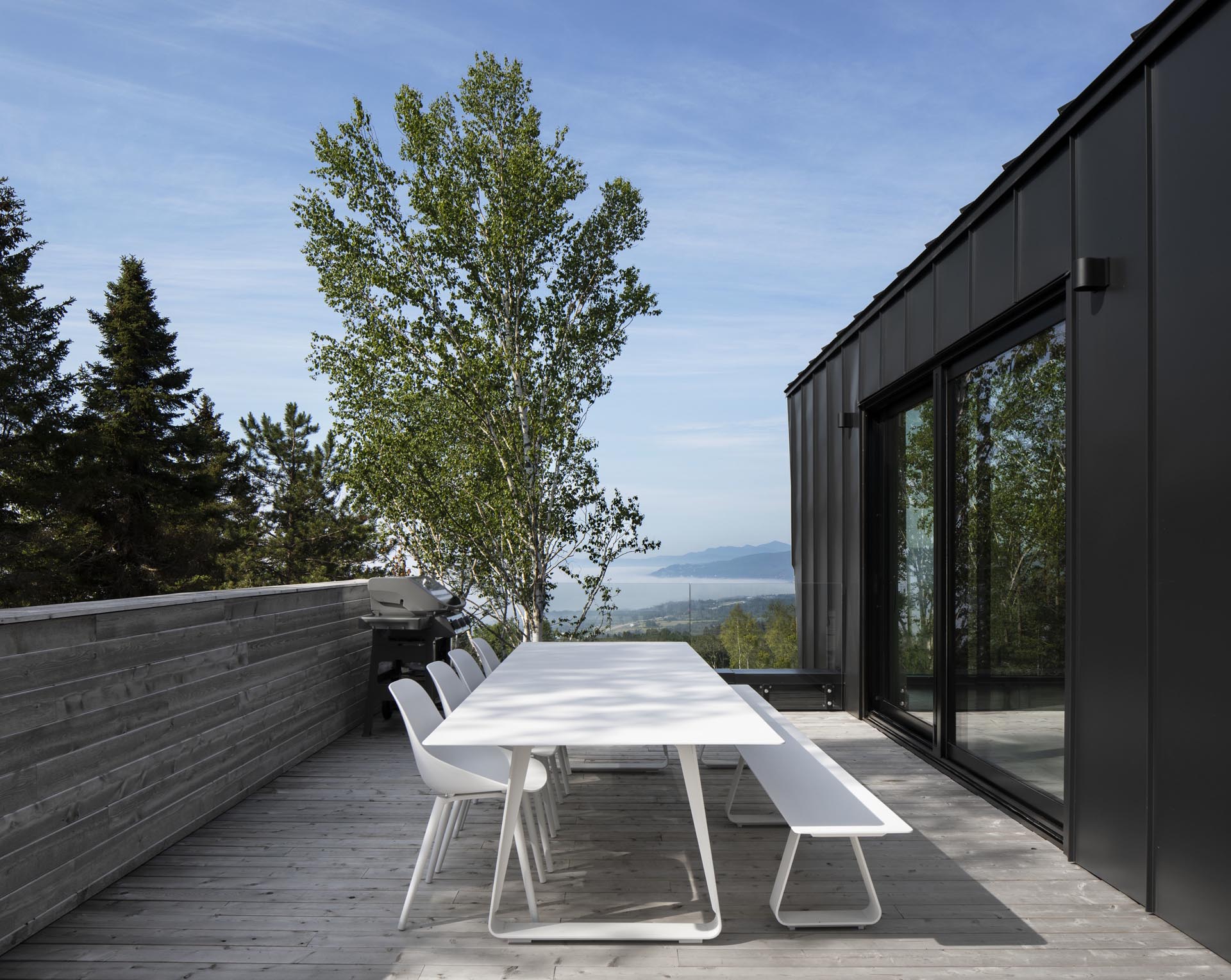 A large sliding black-framed glass door opens to a deck for outdoor dining.