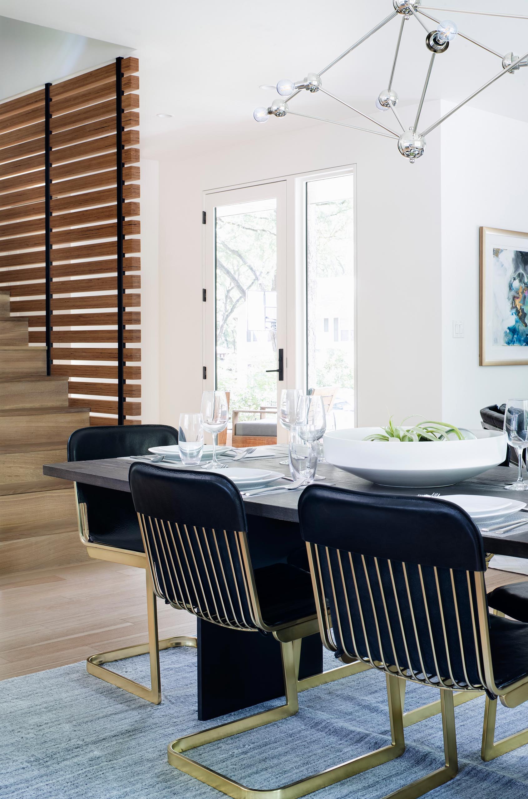 A modern open plan dining area with metallic dining chairs and a gray rug.