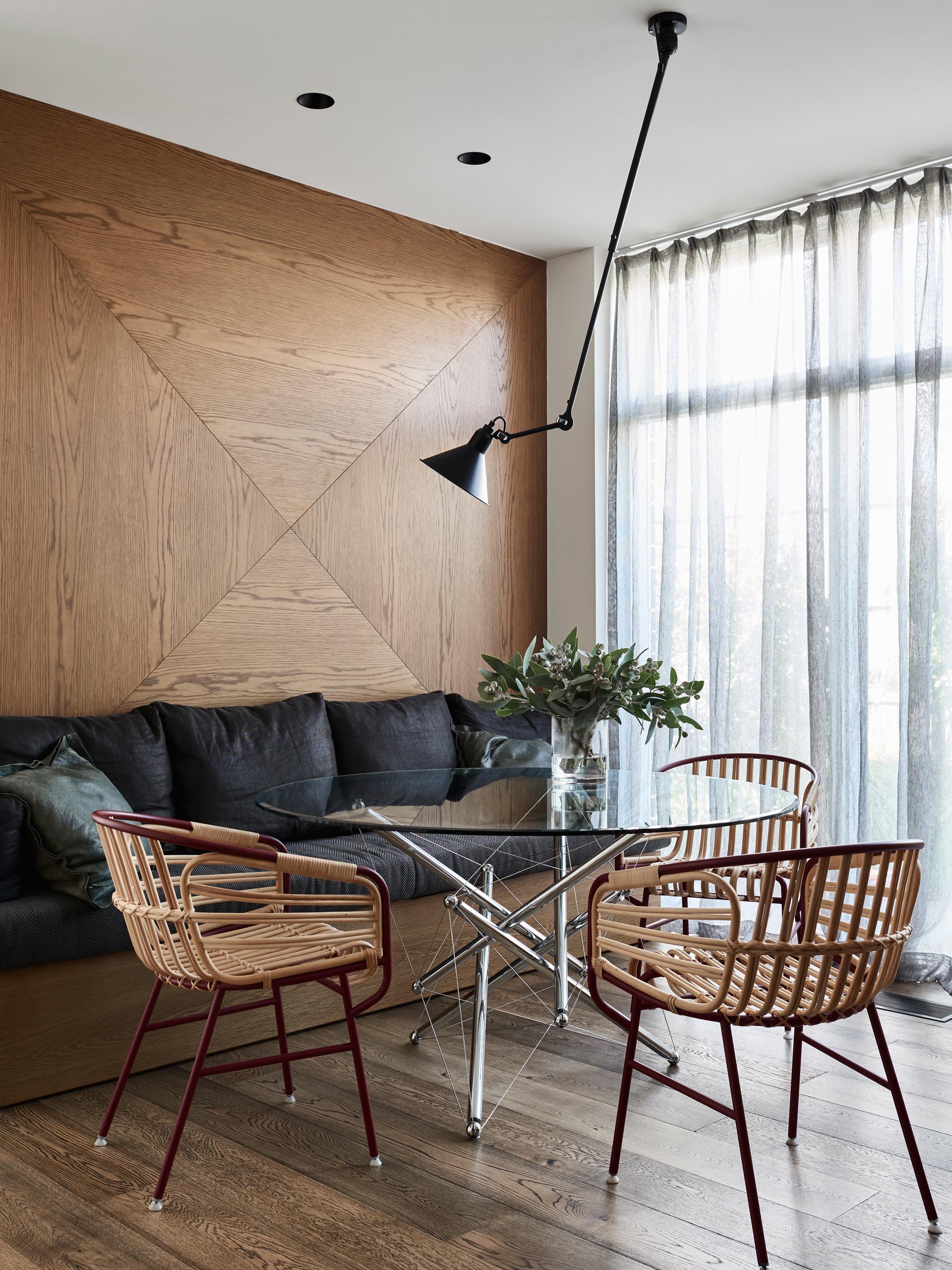 In this dining room, a wood accent wall provides a backdrop for a built-in bench with black cushions.