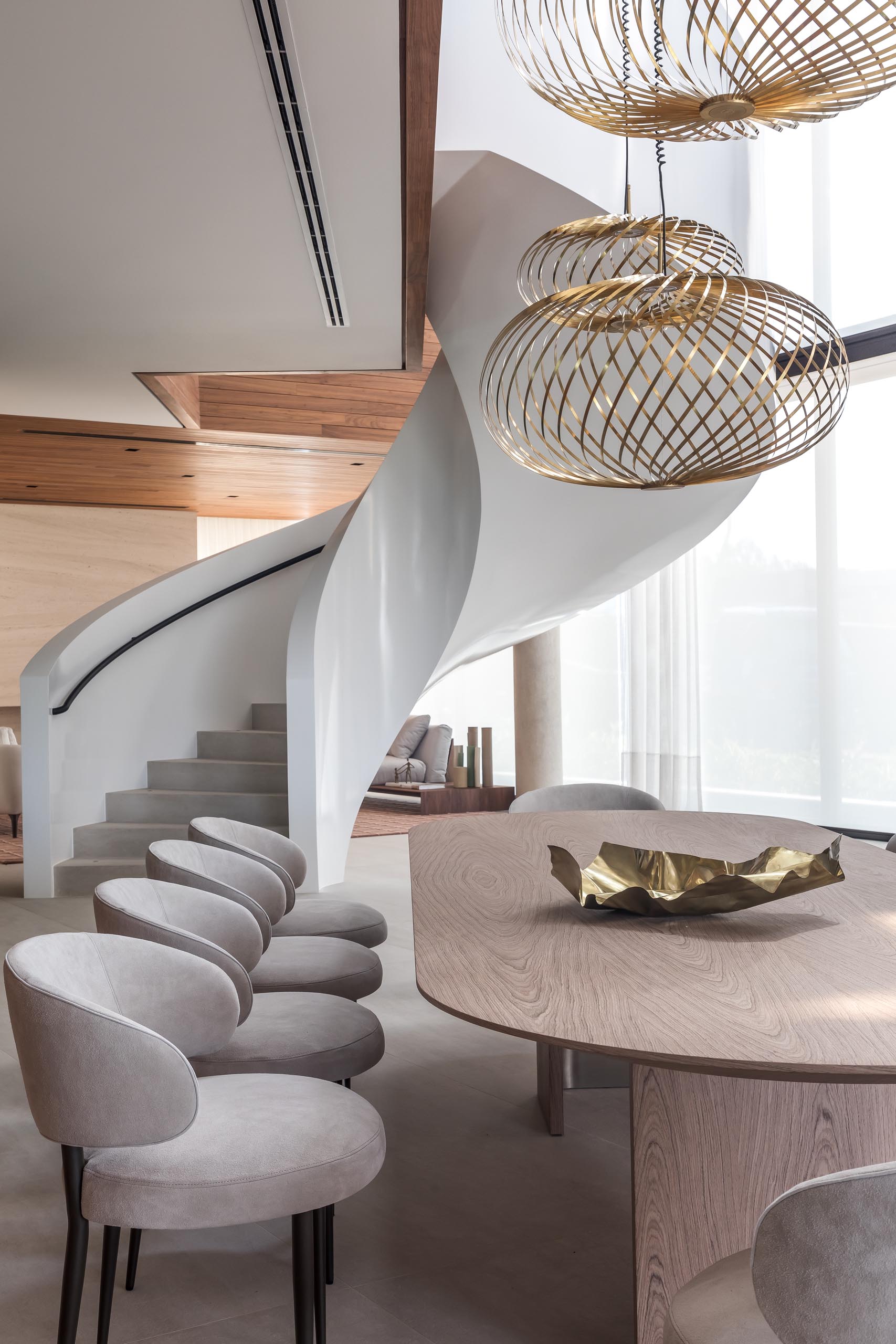 Sculptural metallic pendant lights hang above the rounded dining table in this modern dining room.