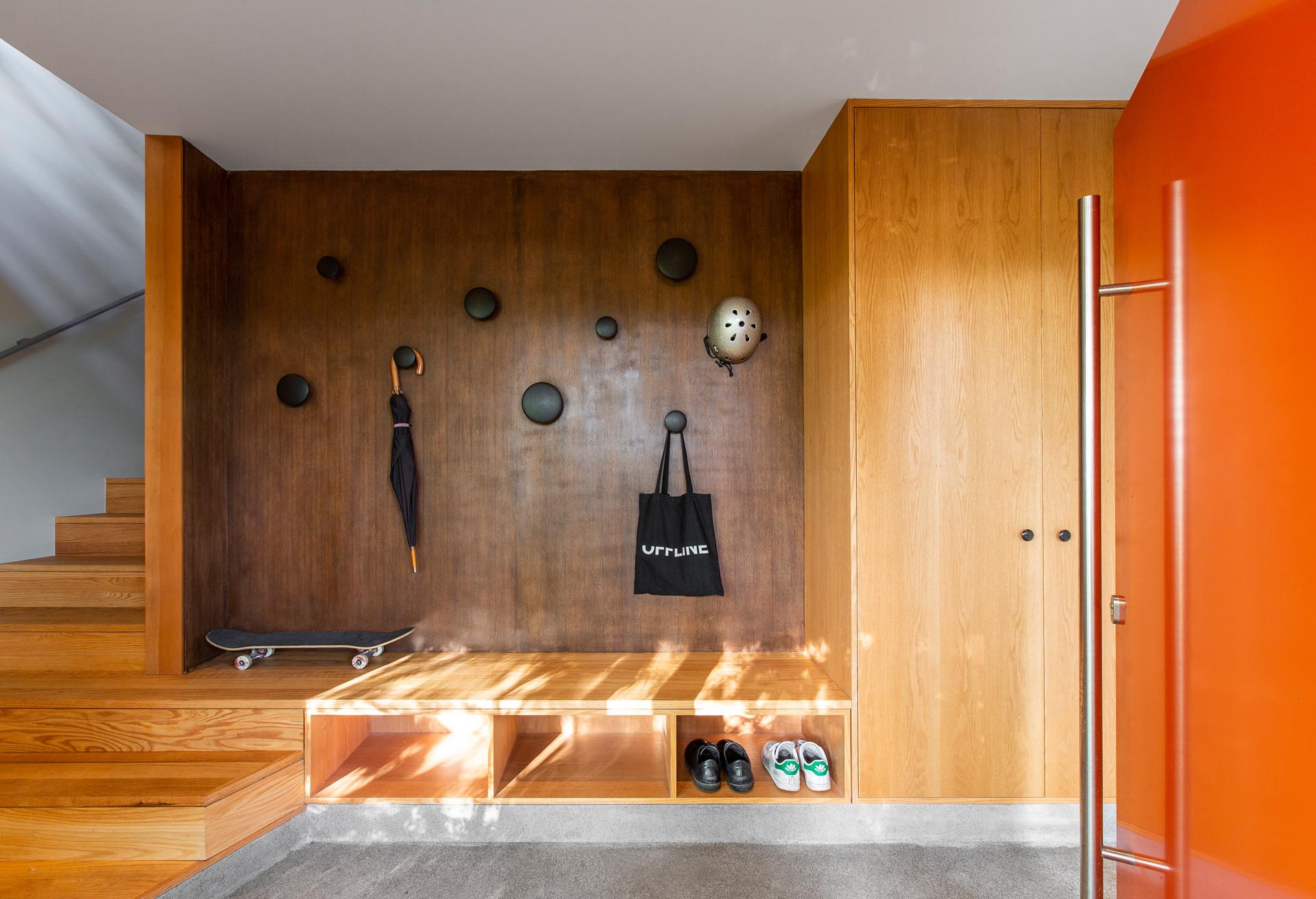 A black walnut plywood wall has been paired with red oak casework to create a modern entryway.