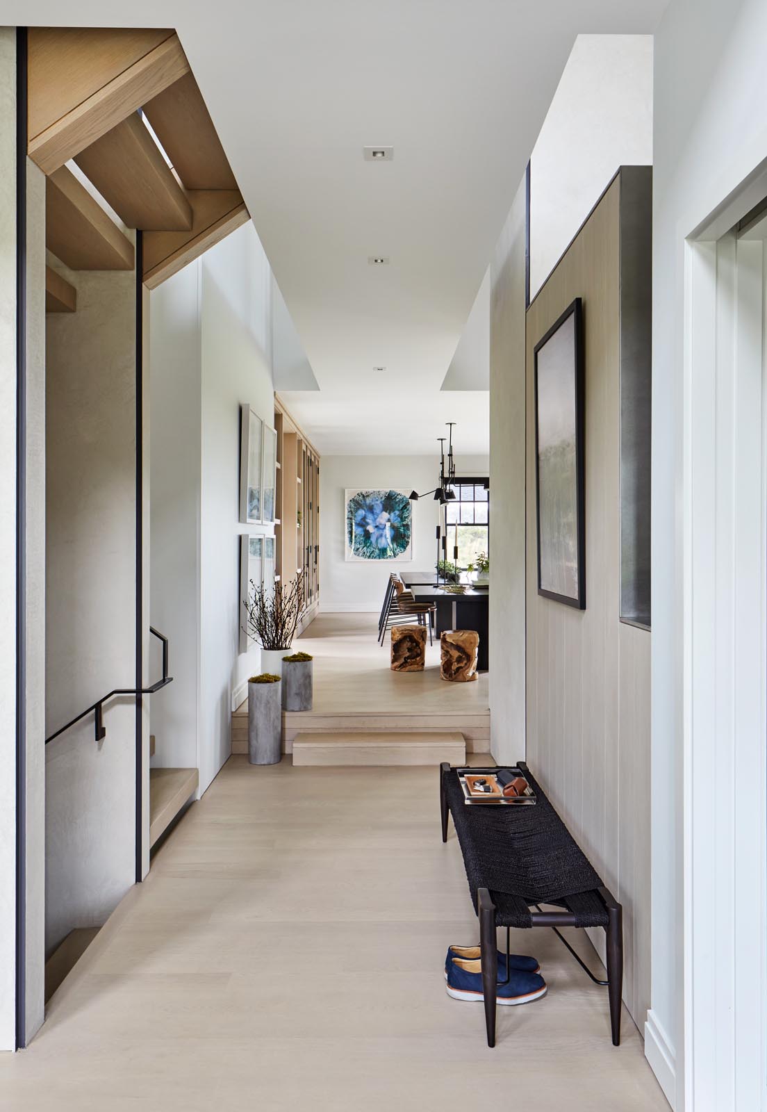 A modern entryway furnished with a simple black bench and artwork.