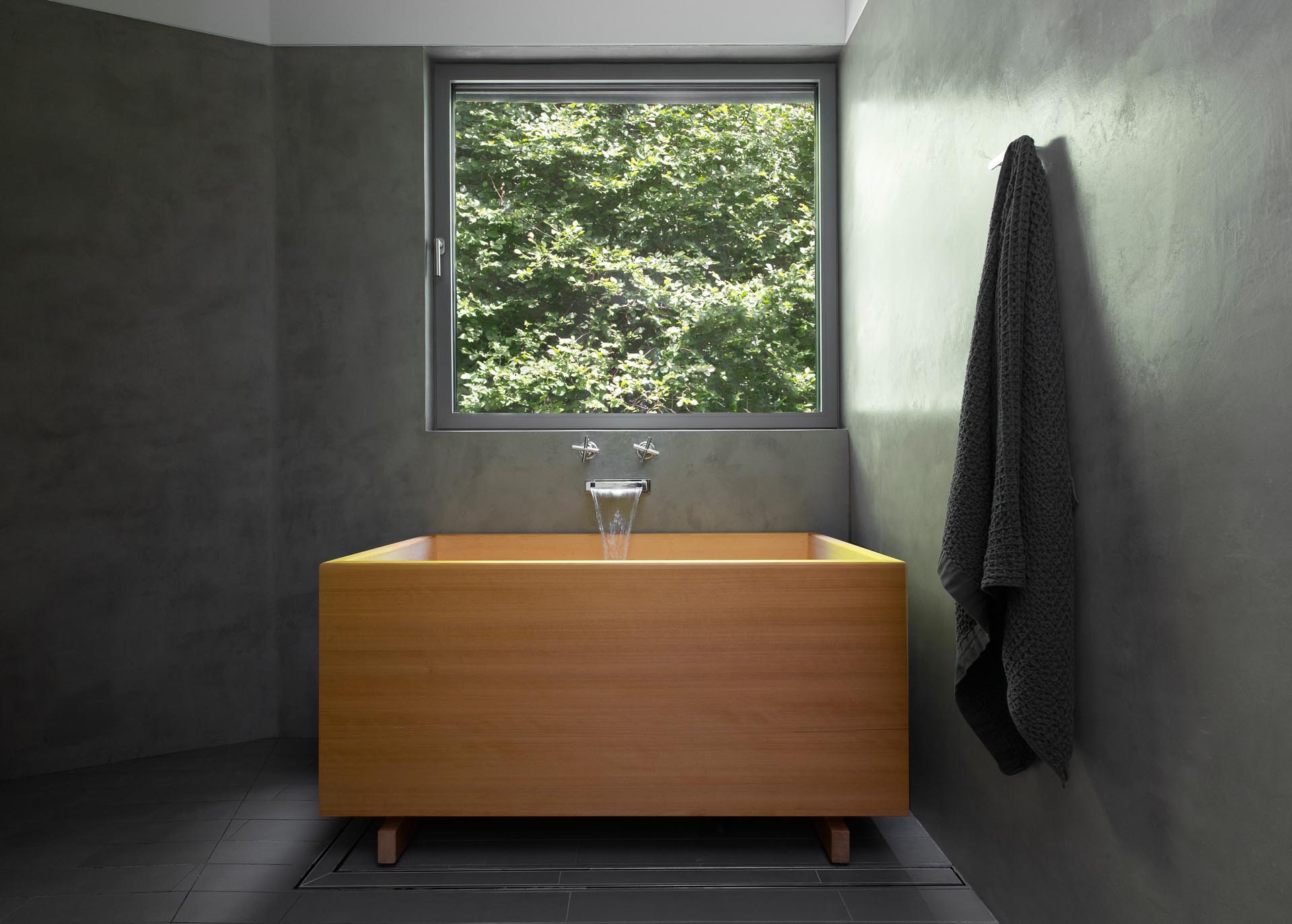 A modern bathroom with dark gray walls and a wood Japanese soaking tub.