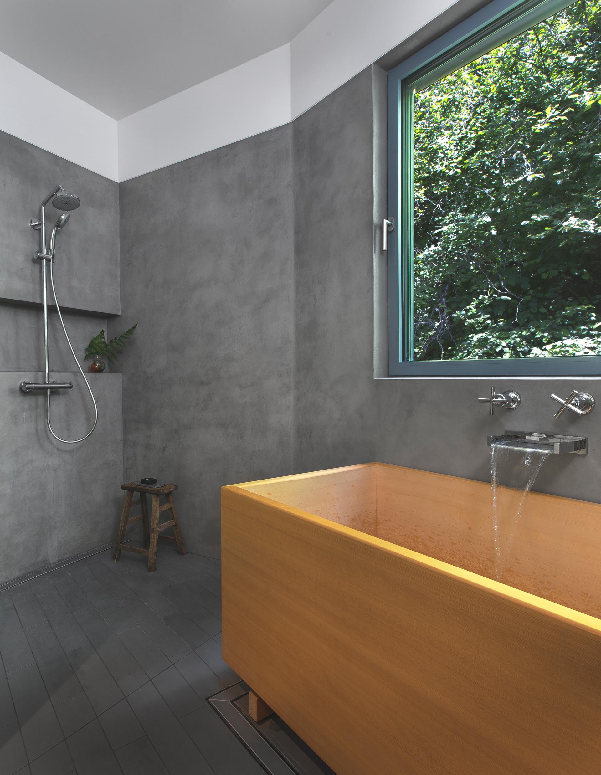 A modern bathroom with dark gray walls and a wood Japanese soaking tub.