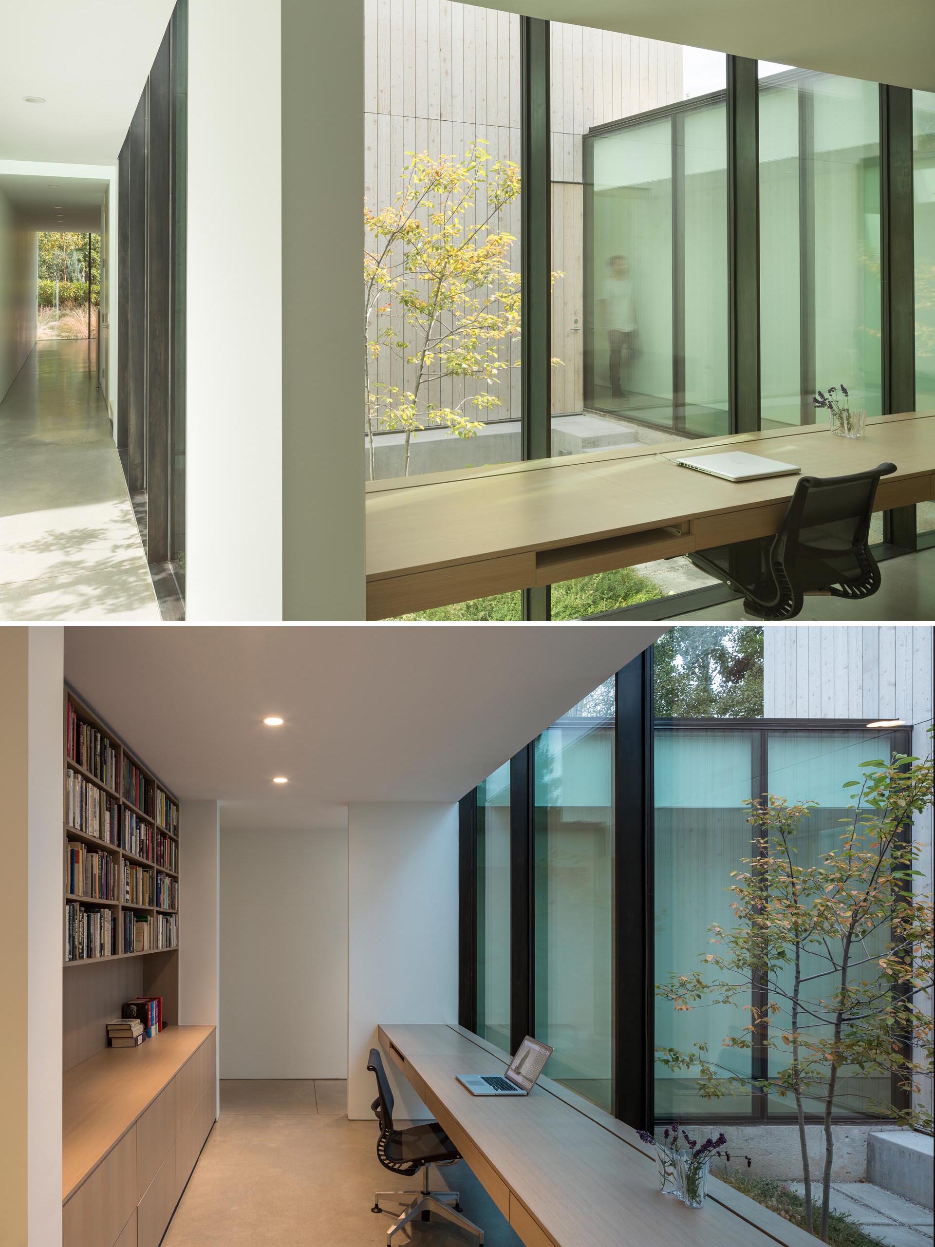 A modern home office with a custom desk and shelving, that's located in a hallway lined with floor-to-ceiling windows.