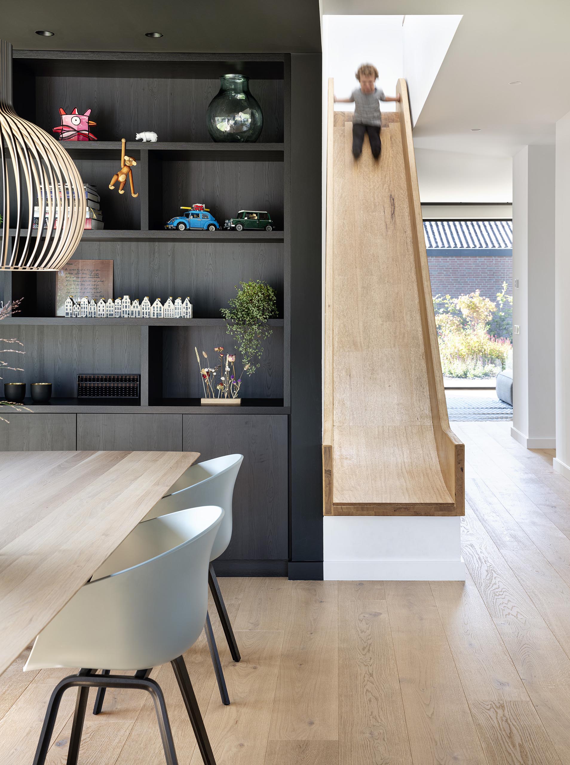 A fun element in the form of a wood slide is a quick way to reach the living spaces from the upper floor of the home.