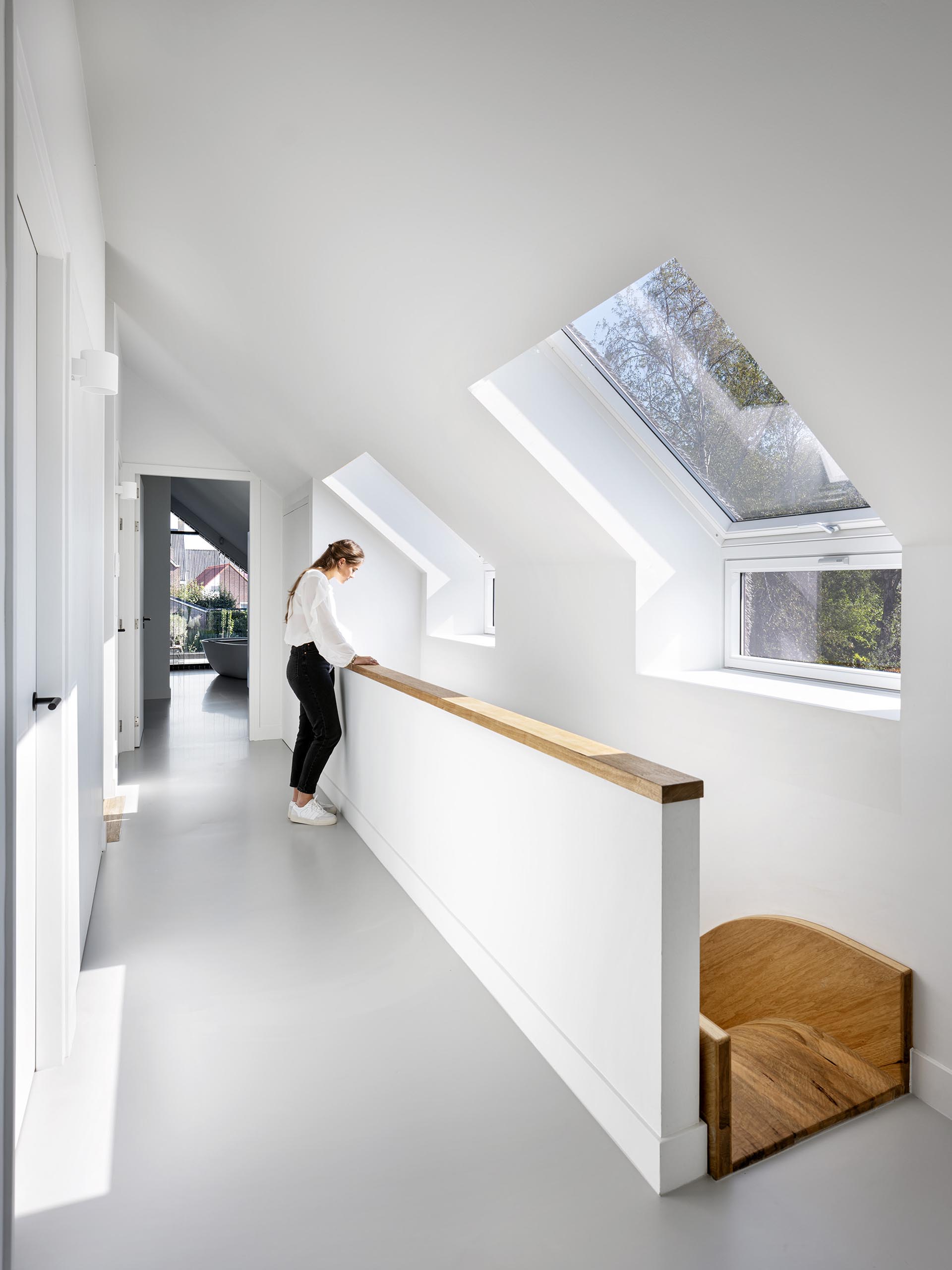 A modern house with an open hallway that connects to the bedrooms and shows the top of an indoor wood slide.