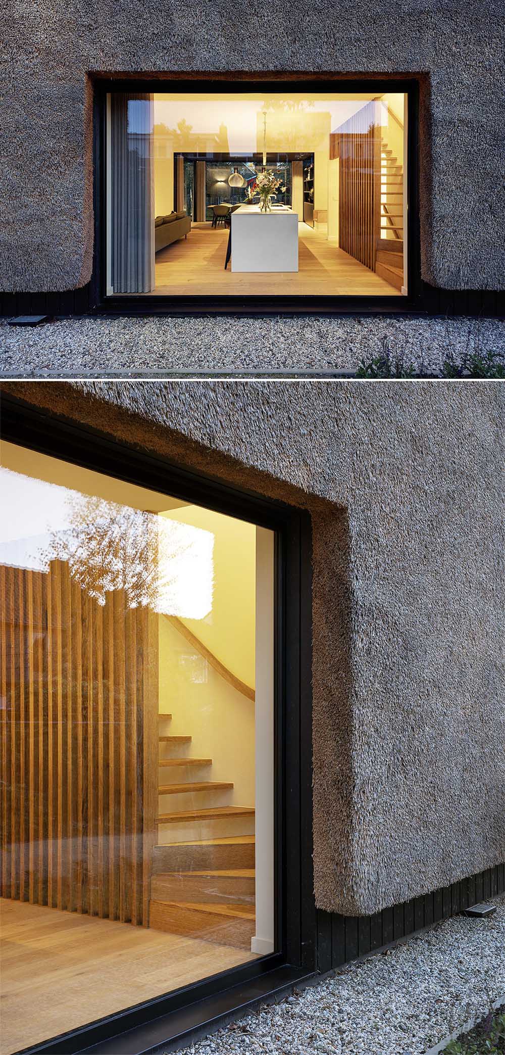 The exterior of this modern house is covered in thatch, which runs vertically down from the rooftop and along the sides of the house. The thatched roof is contrasted by wood with a black finish.