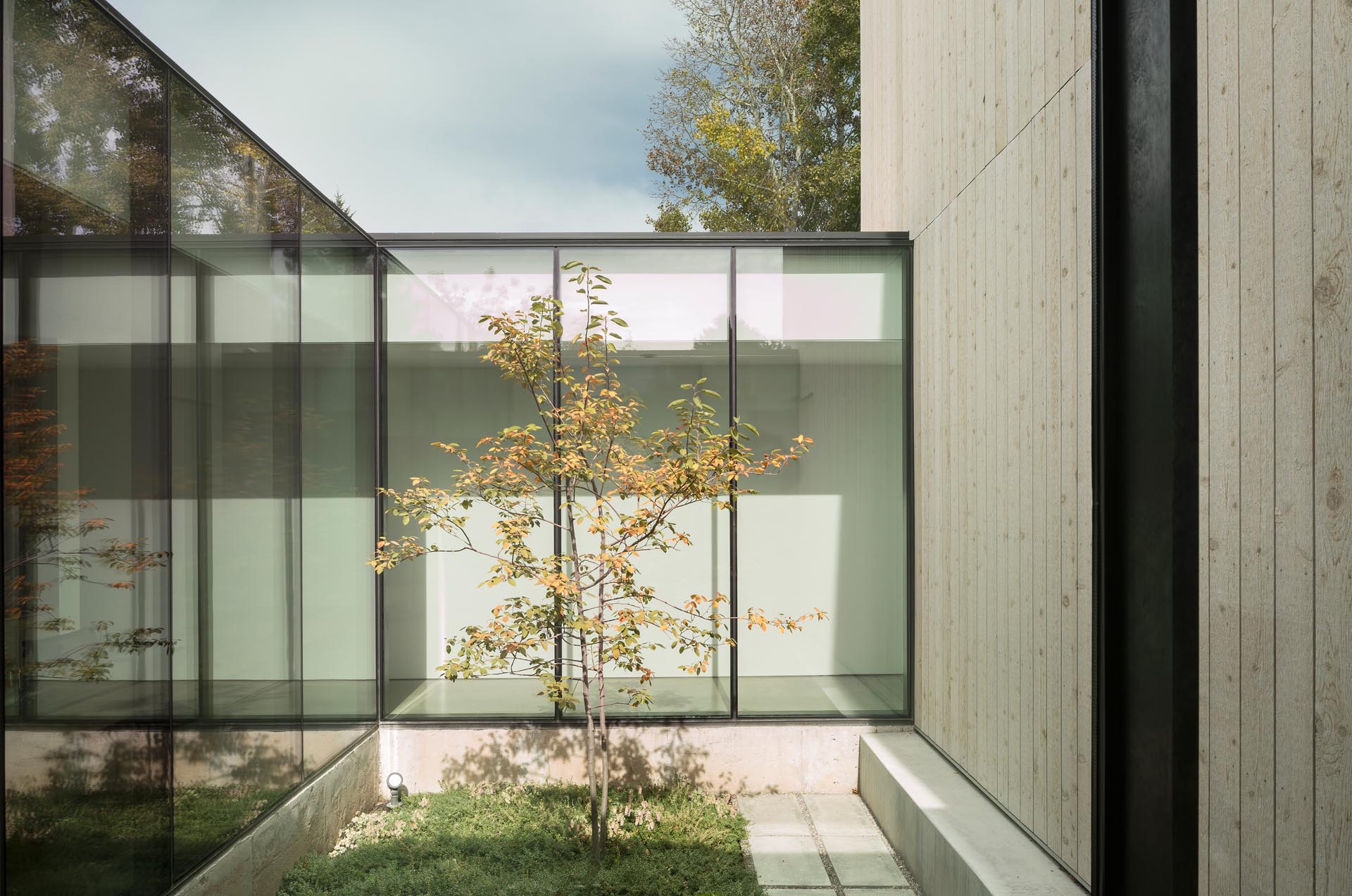 A modern home with a long hallway, floor-to-ceiling windows, and concrete floors.