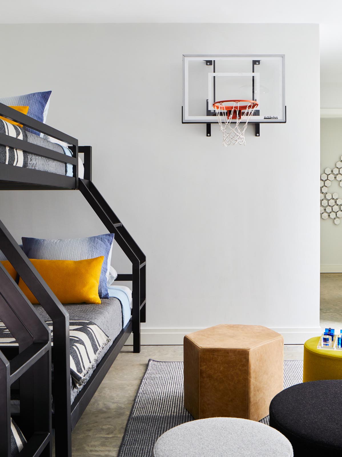 A kids bedroom with bunk beds and a basketball hoop.