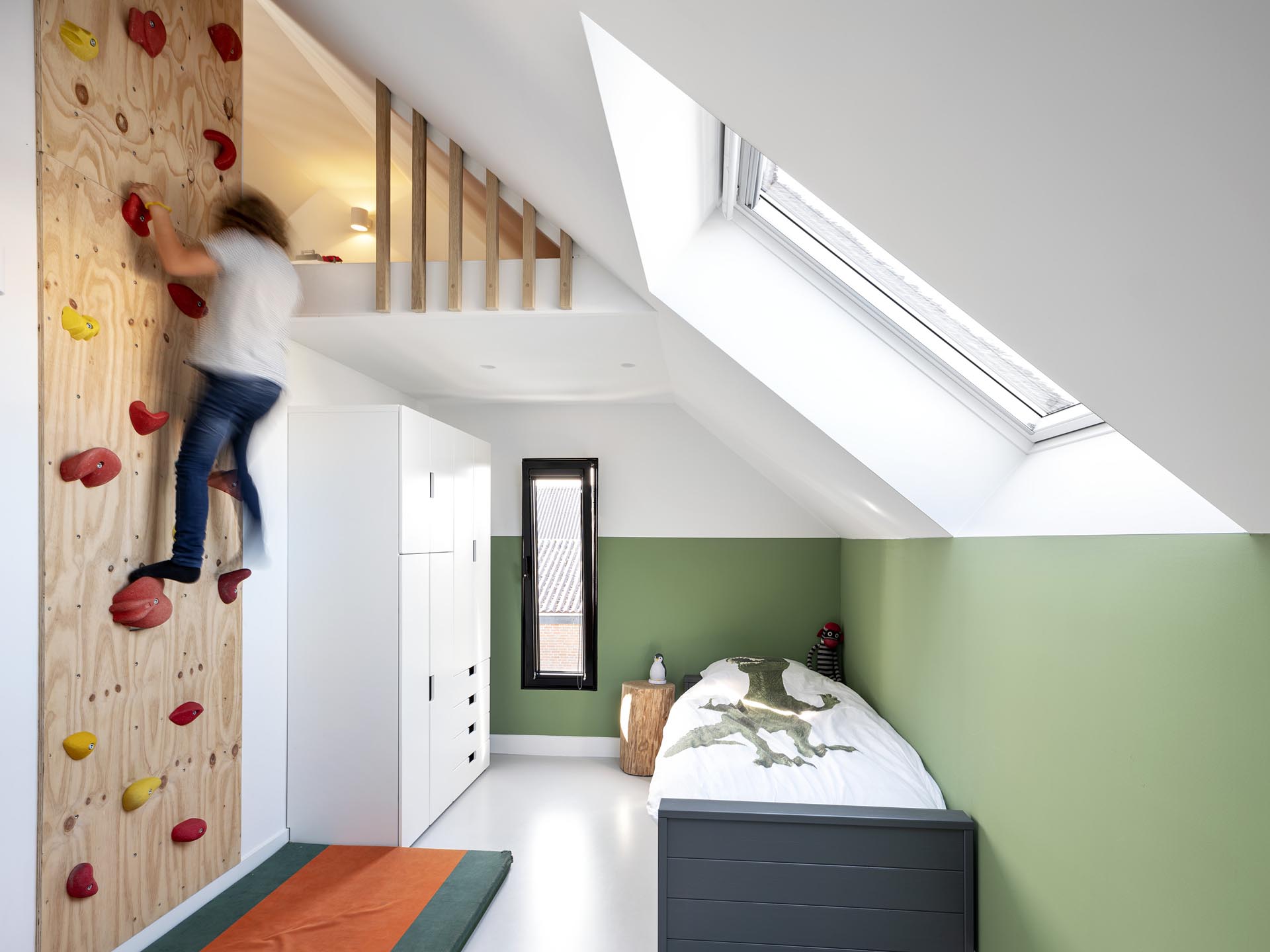 In this modern child's bedroom, there's a rock climbing wall that allows for access to a small lofted area.