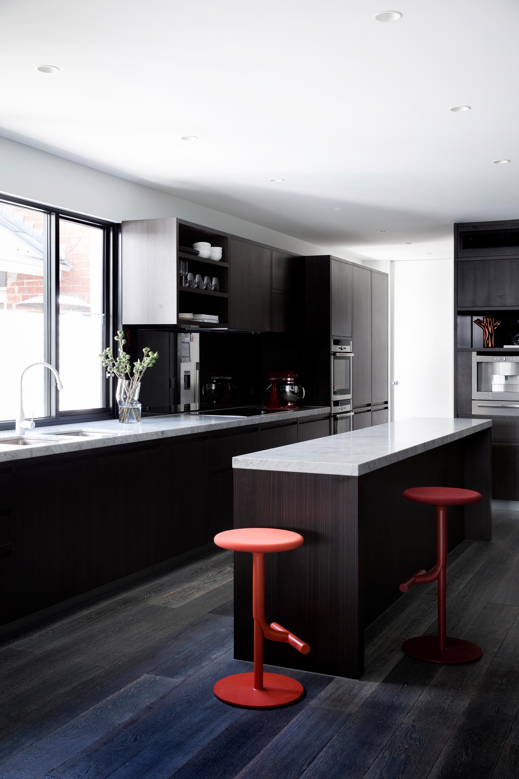 A modern kitchen with dark wood cabinets and light gray marble countertops.