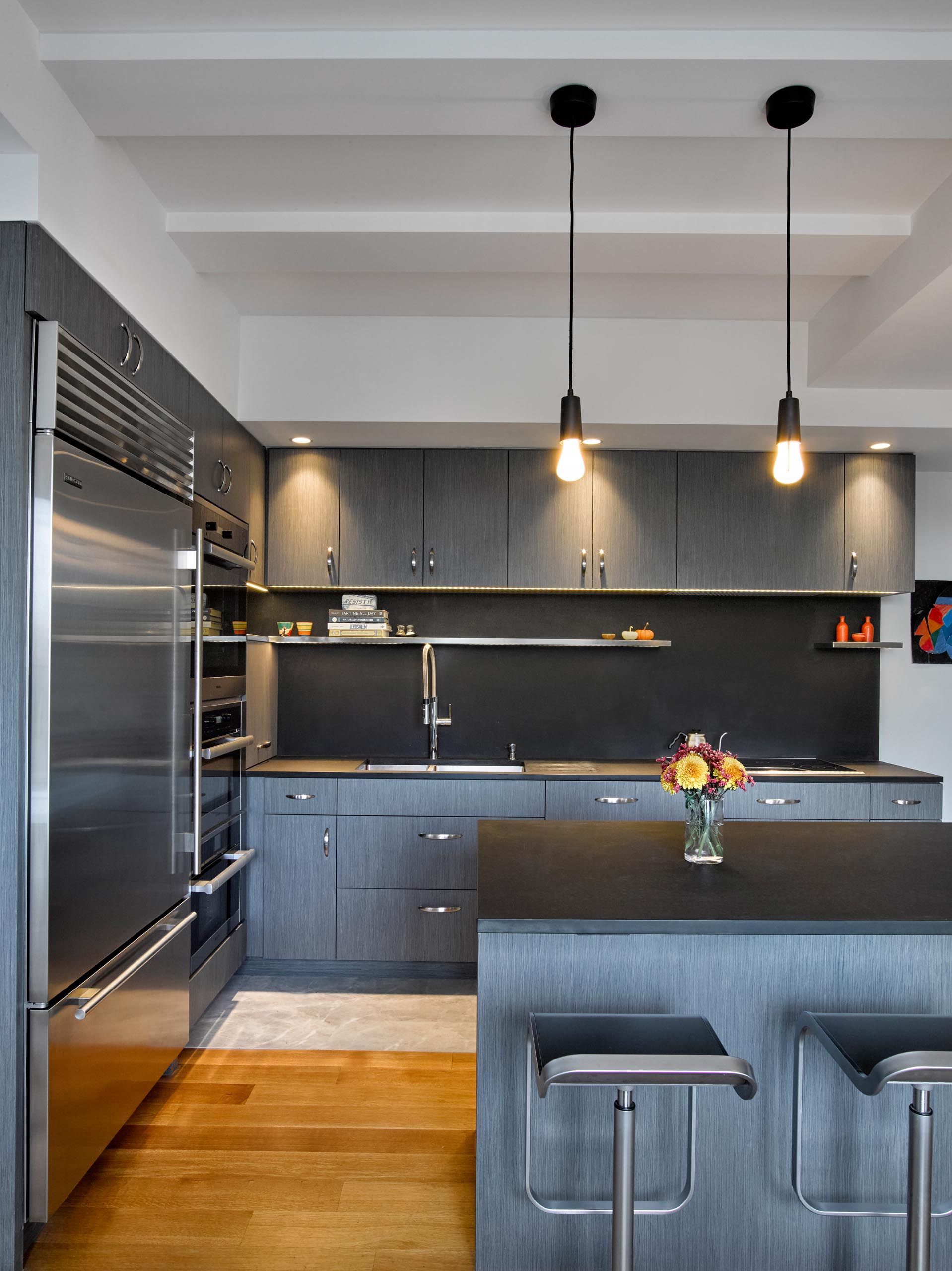 A modern kitchen with gray cabinets, LED undermount lighting, and Paperstone countertops and backsplash.