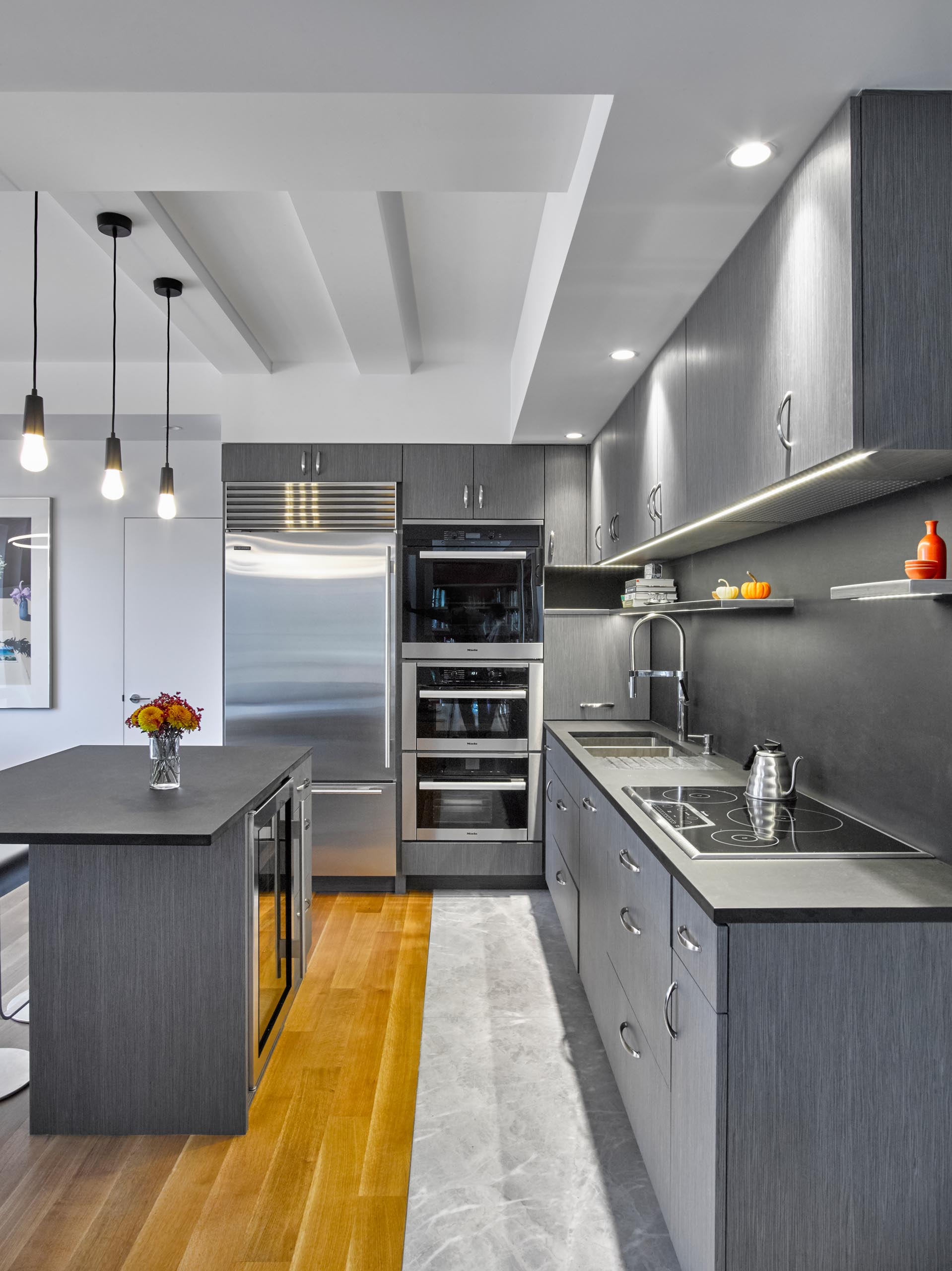 A modern kitchen with gray cabinets, LED undermount lighting, and Paperstone countertops and backsplash.