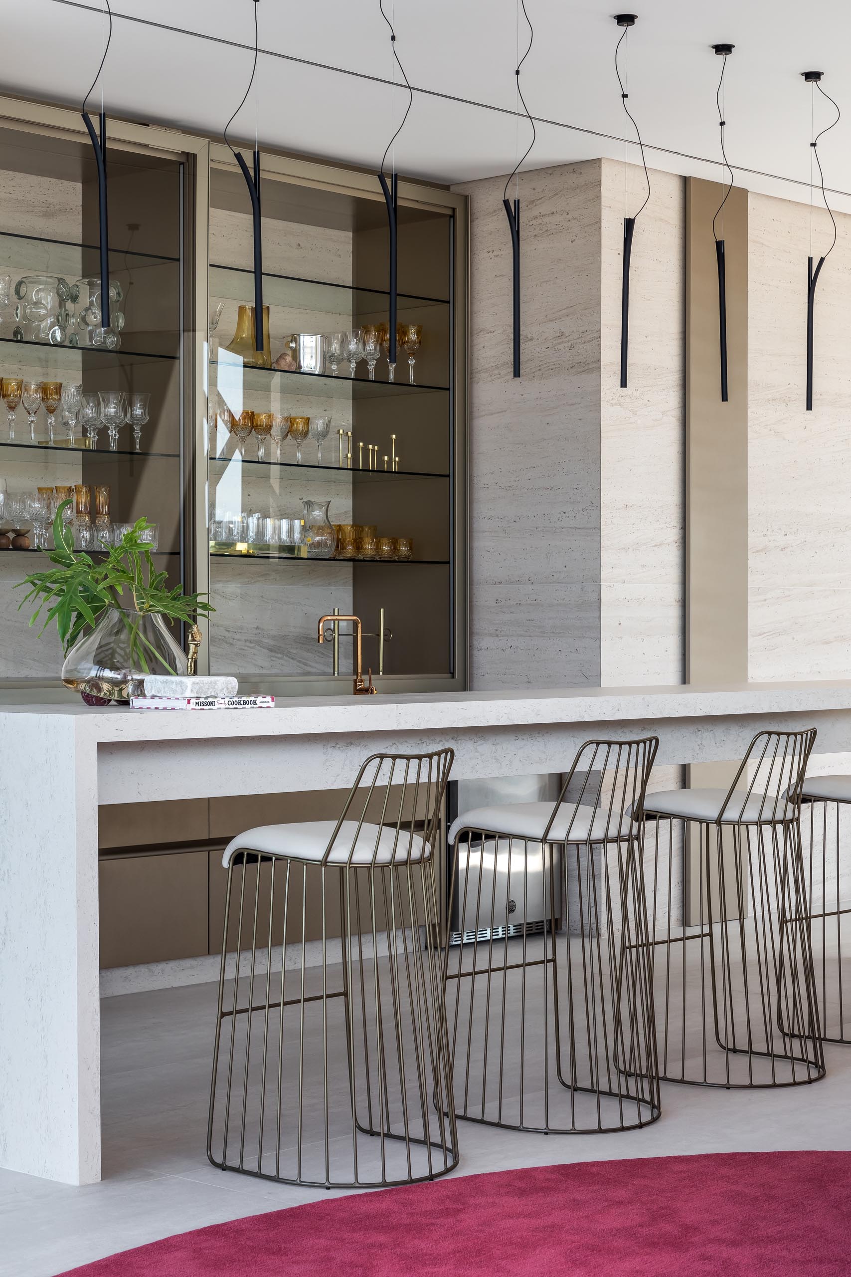 This modern home bar has a long narrow island and glass shelving.