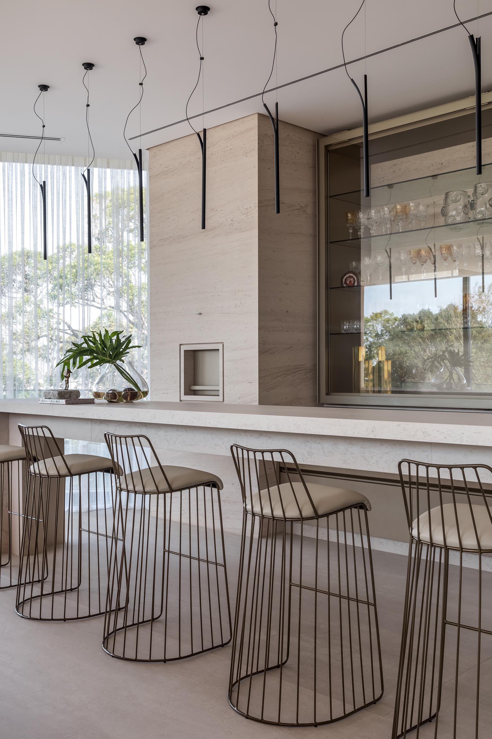 This modern home bar has a long narrow island and glass shelving.