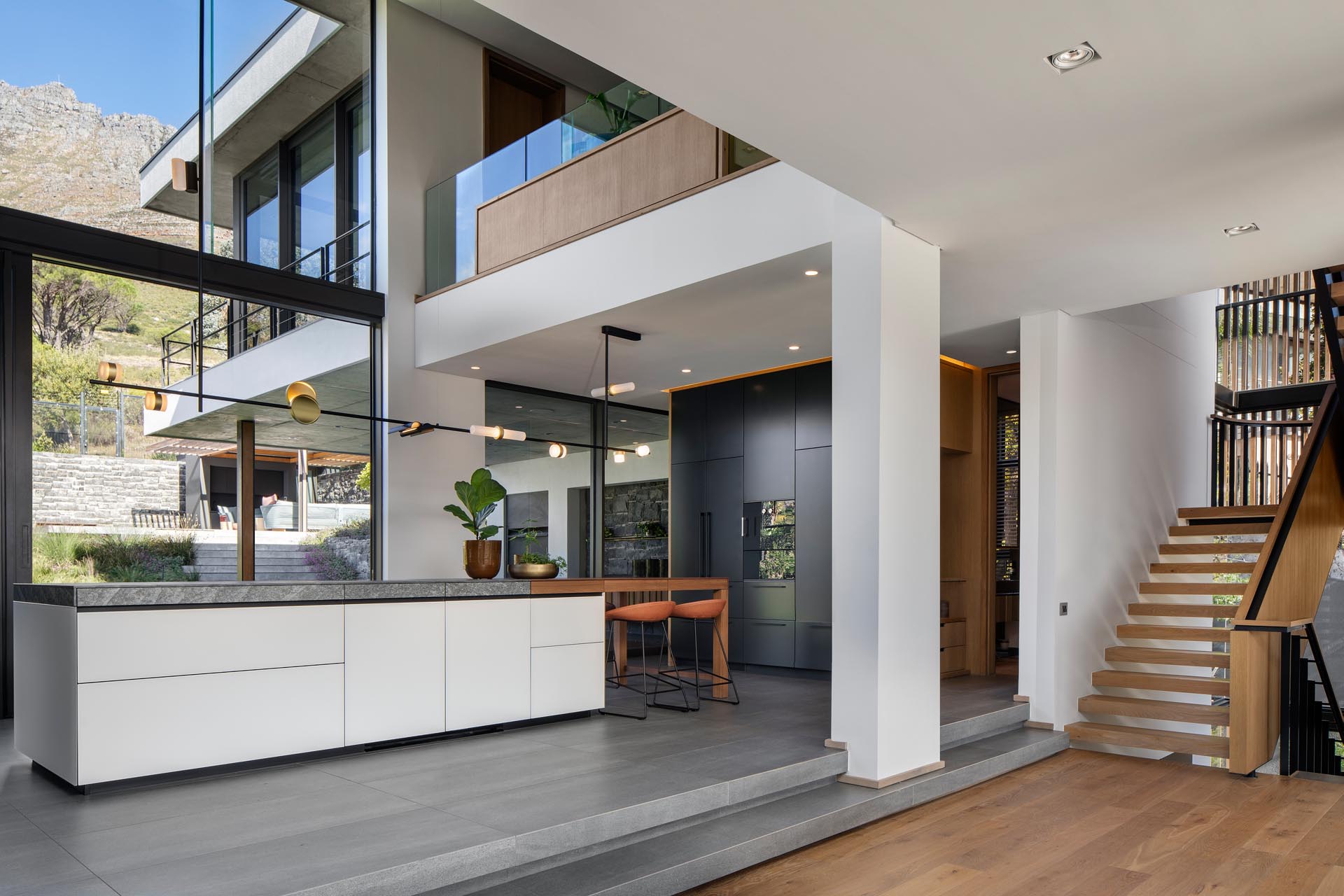 A modern kitchen with minimalist cabinets, a high ceiling, and plenty of windows.