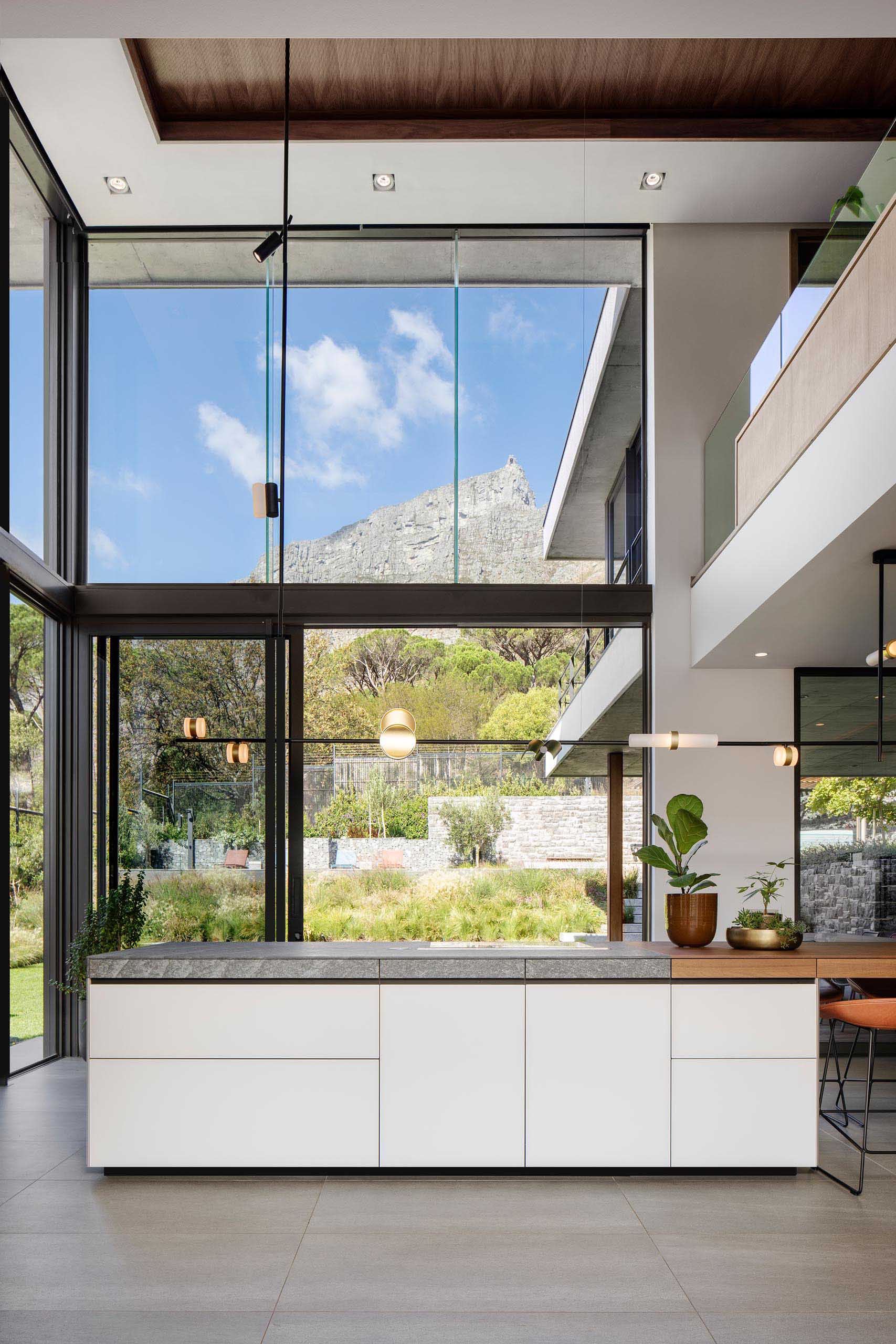 A modern kitchen with minimalist cabinets, a high ceiling, and plenty of windows.