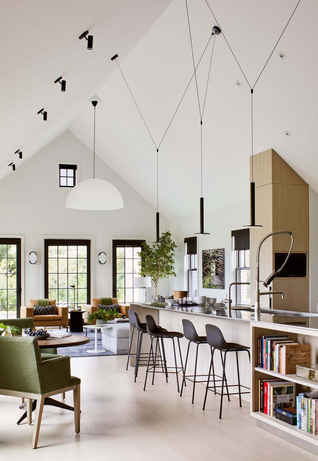In the kitchen, there's minimalist light wood cabinets and a long island with black pendant lights and room for multiple stools.
