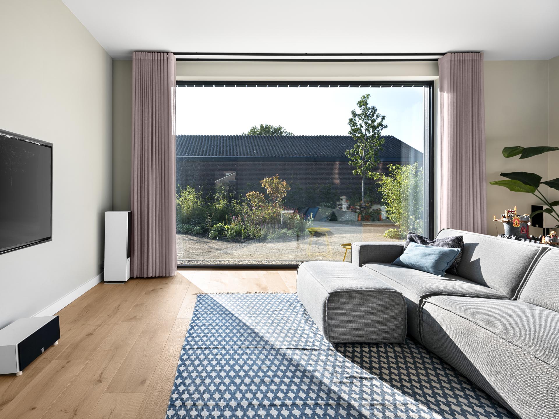 A modern living room with a large window that provides ample natural light and views of the garden.