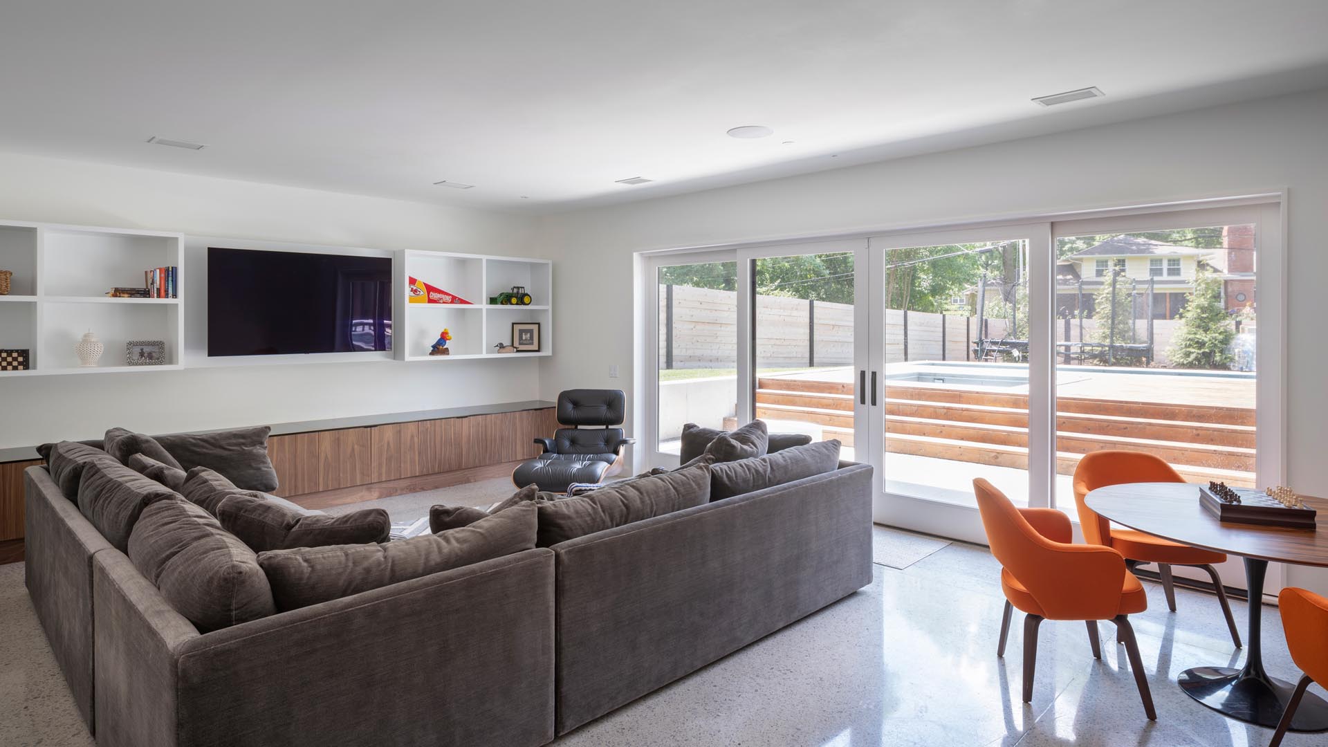 A casual living room with an L-shaped sofa and sliding doors that open to the pool and yard.