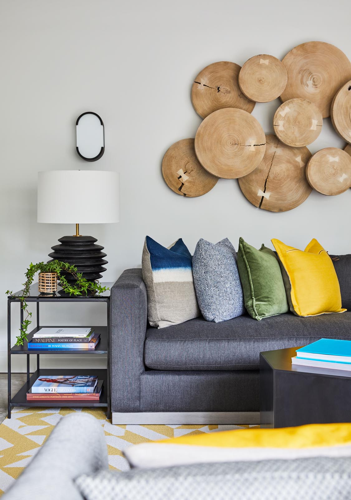 A modern media room with yellow accents, and a large wood art piece on the wall.