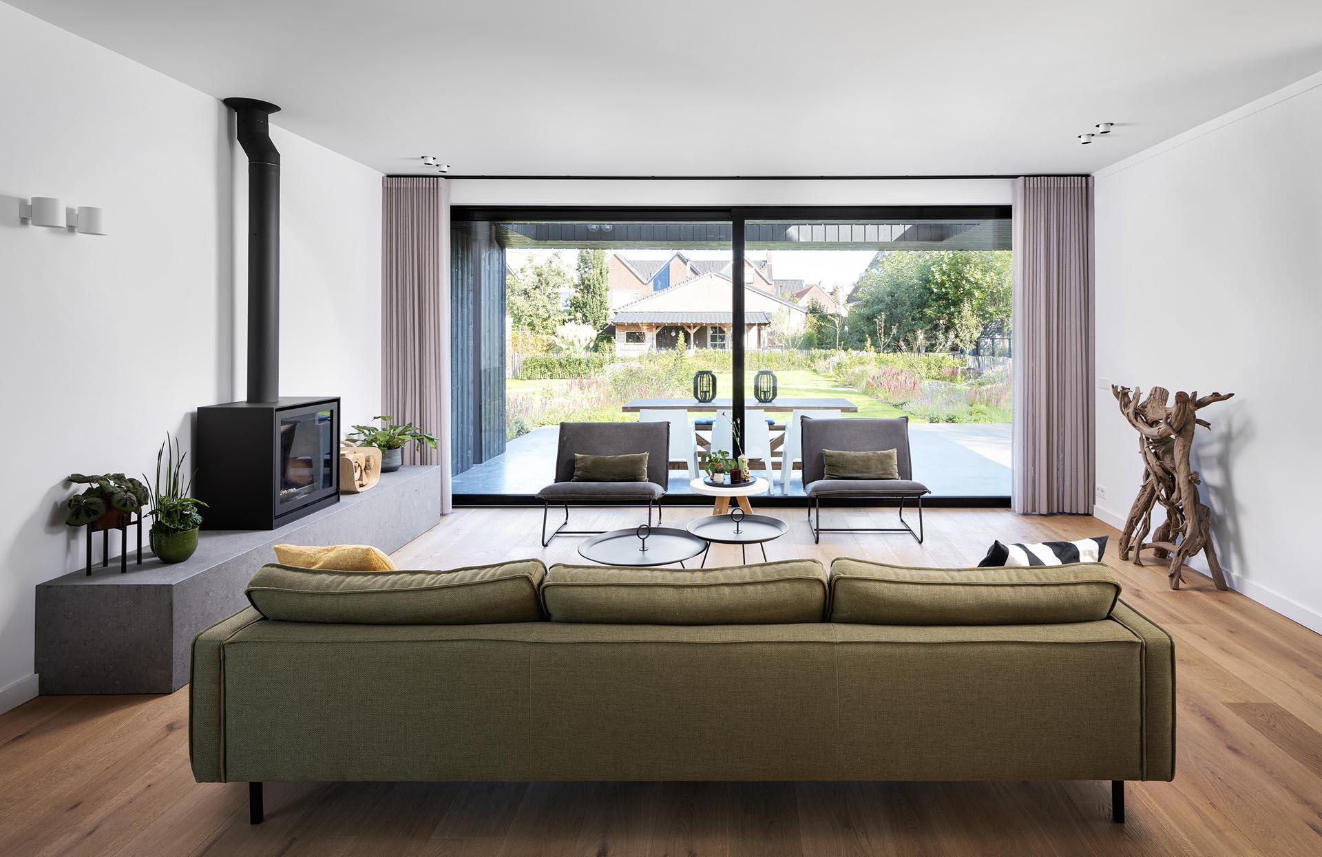 Inside a modern home, the furnishings have been kept minimal, while large sliding doors open the living room to an outdoor patio that's been set up for alfresco dining.