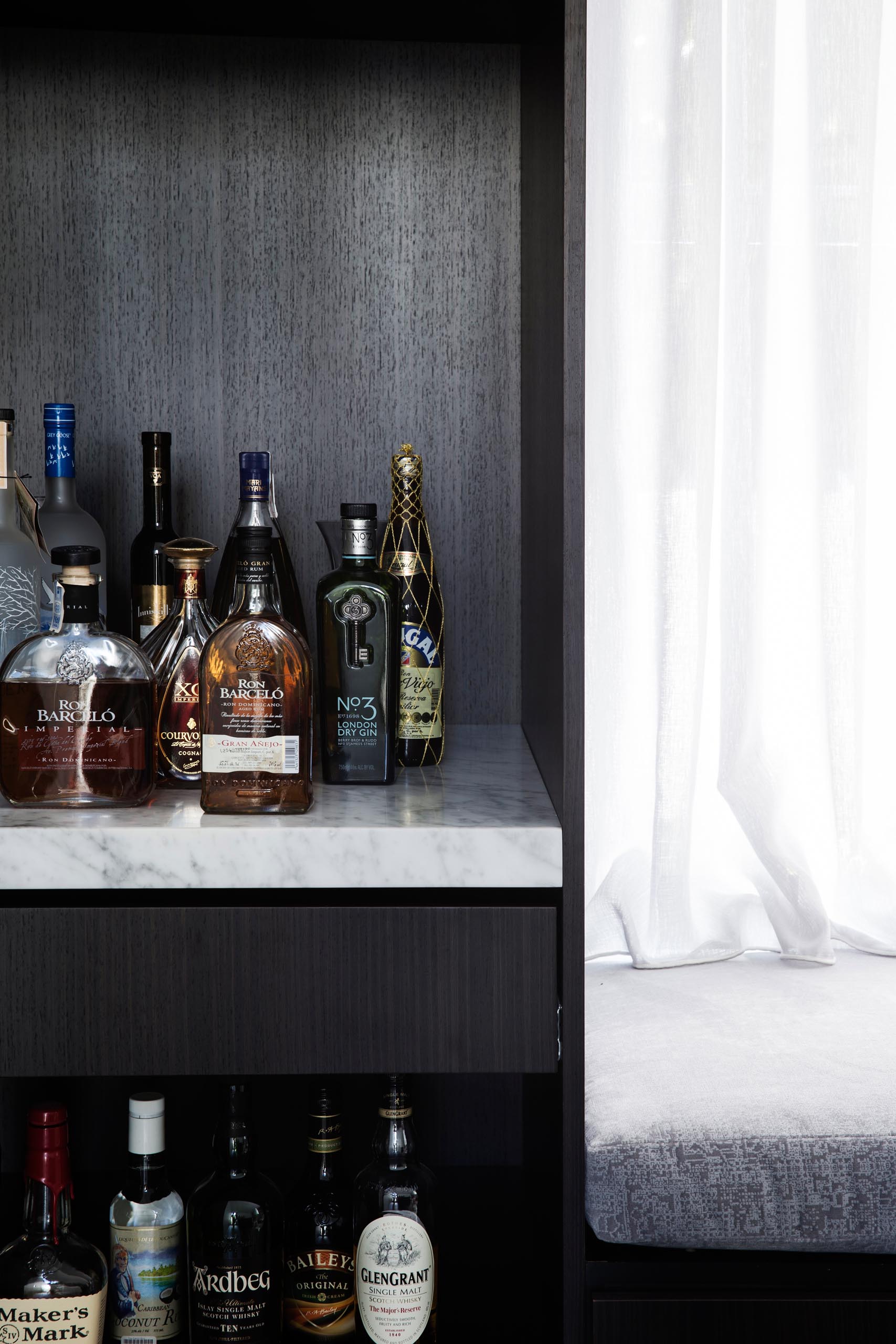 A modern living room with a built-in window seat and a hidden home bar.