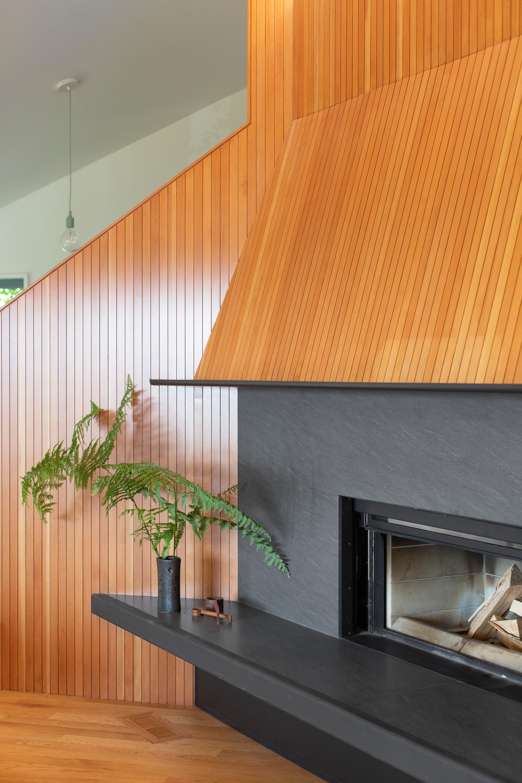 In the living room, custom milled fir surrounds a black fireplace with steel accents, while large windows provide tree views.