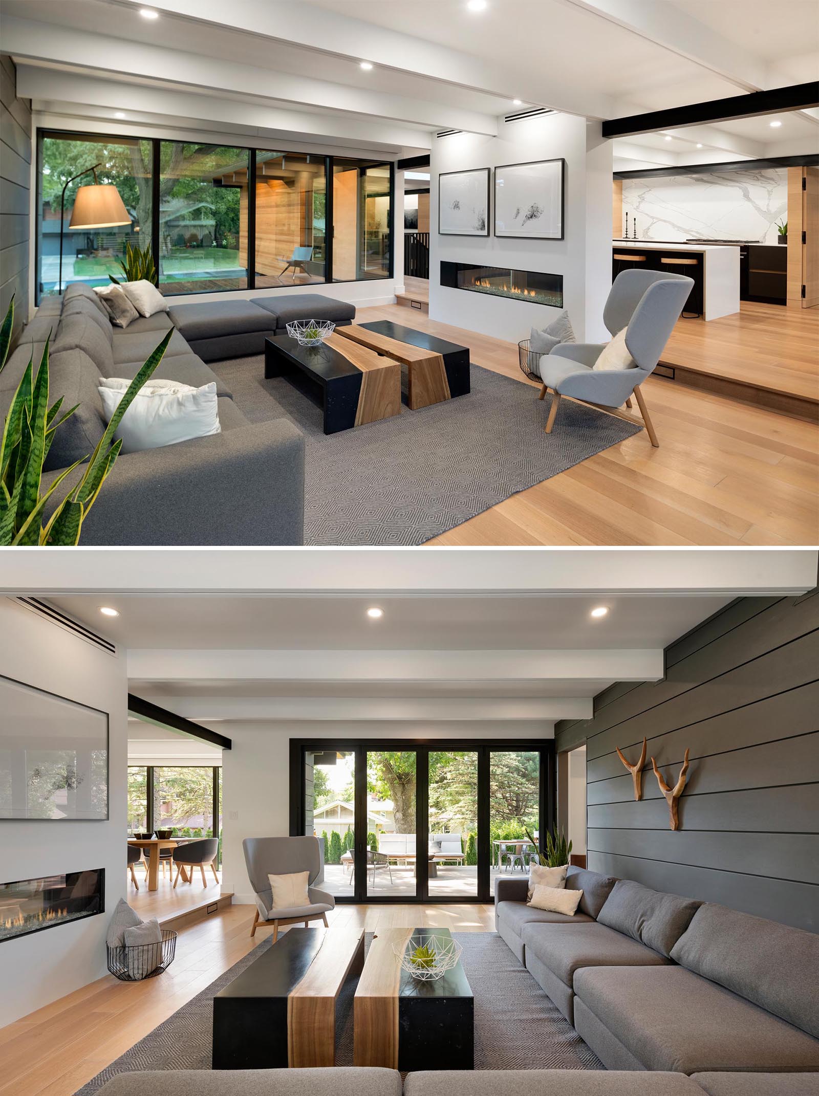 A modern living room with a gray accent wall and matching sofa, and a double sided fireplace.