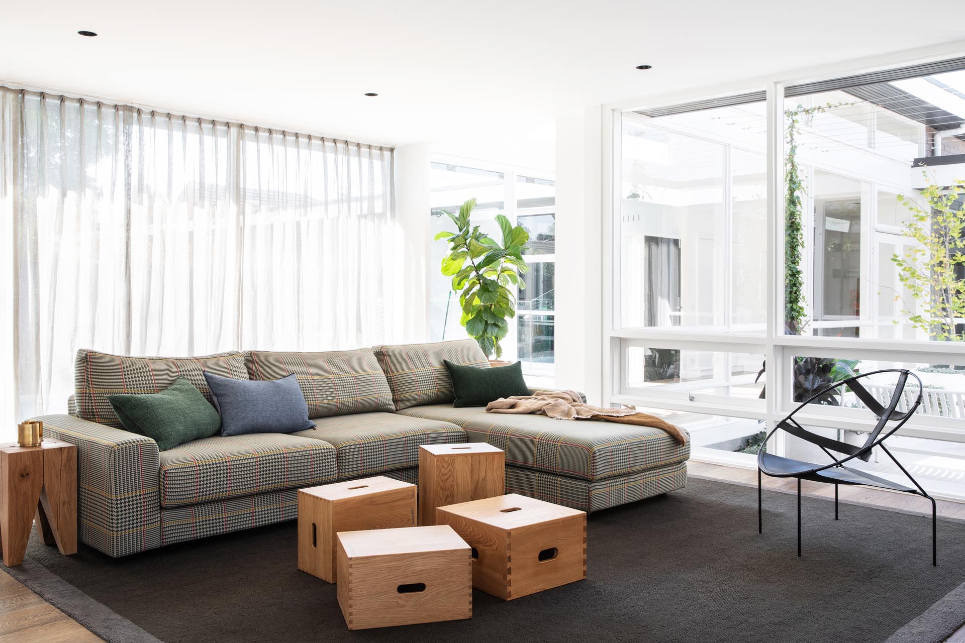 This modern living room is defined by a large dark colored rug, while wood boxes have been used to create a coffee table.