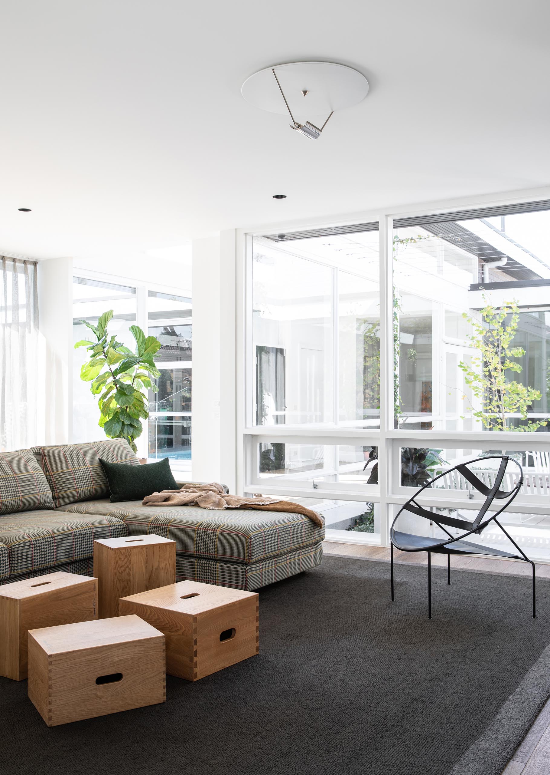 This modern living room is defined by a large dark colored rug, while wood boxes have been used to create a coffee table.