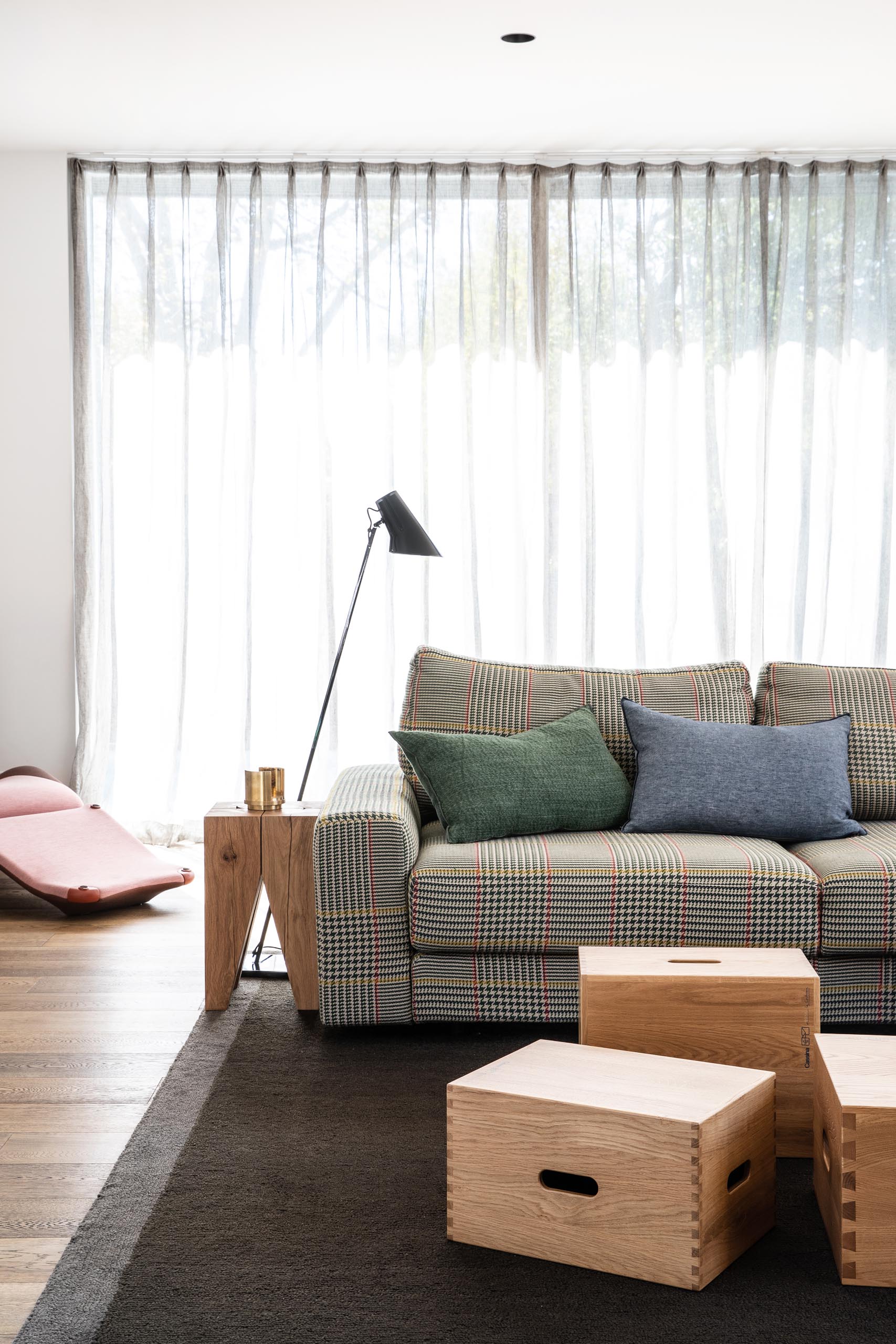 This modern living room is defined by a large dark colored rug, while wood boxes have been used to create a coffee table.