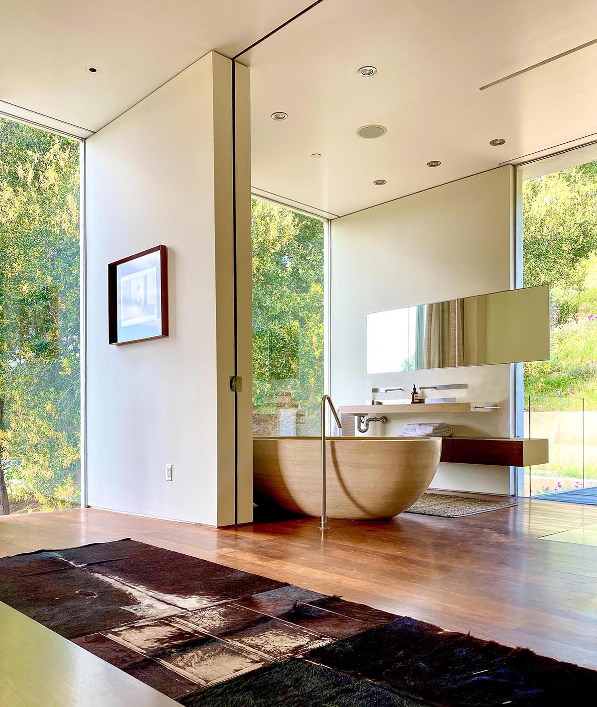 A modern master bathroom includes Portuguese limestone and a soaking tub that's been hand-carved from a single block.