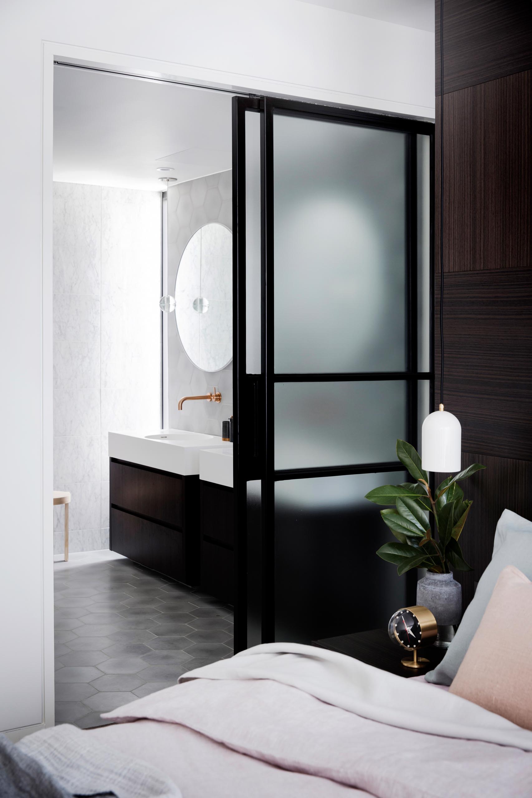 A black framed frosted glass door that slides open to reveal a modern en-suite bathroom.