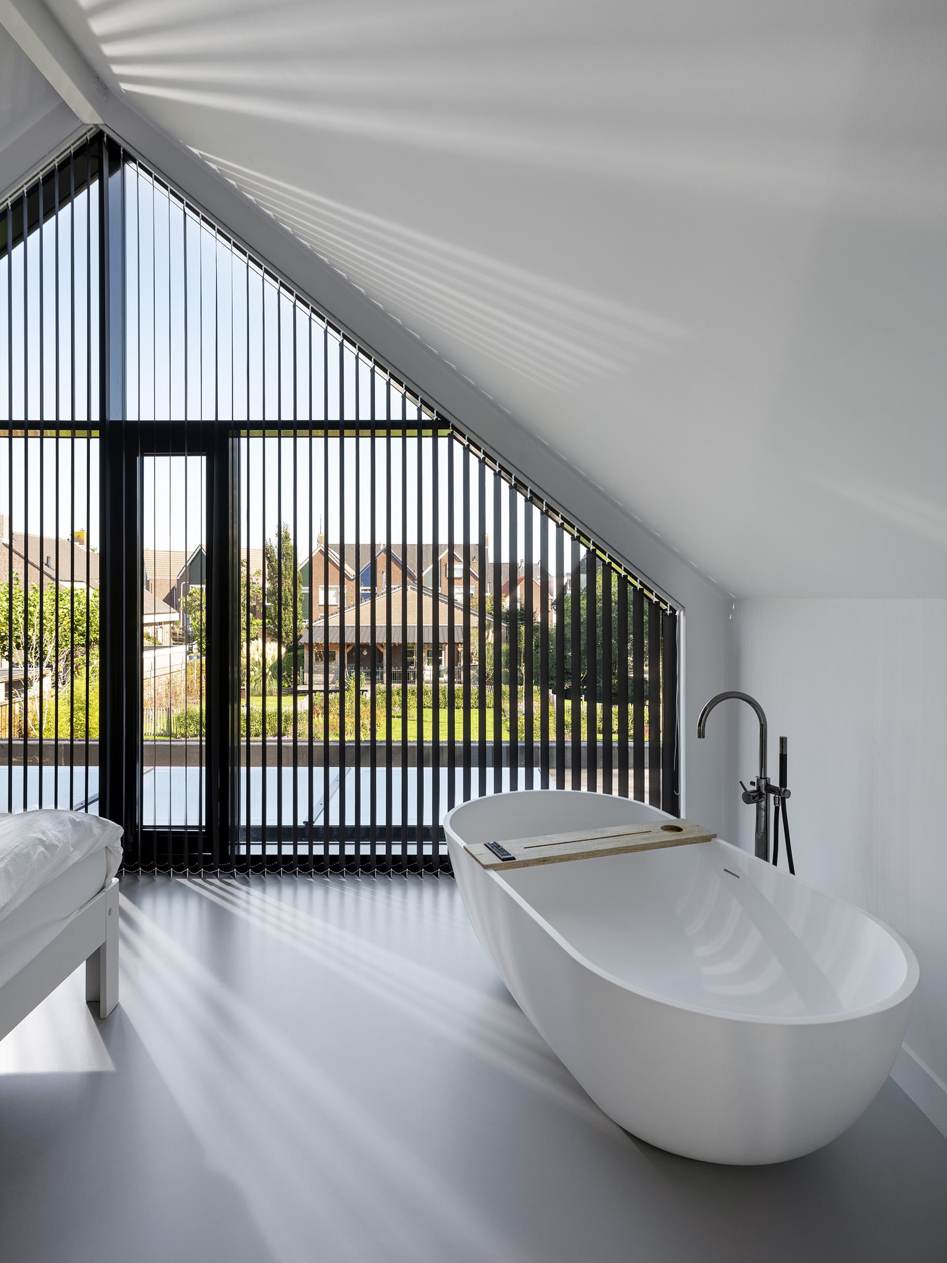 This modern master bedroom has windows that match the roof line and a freestanding bathtub.