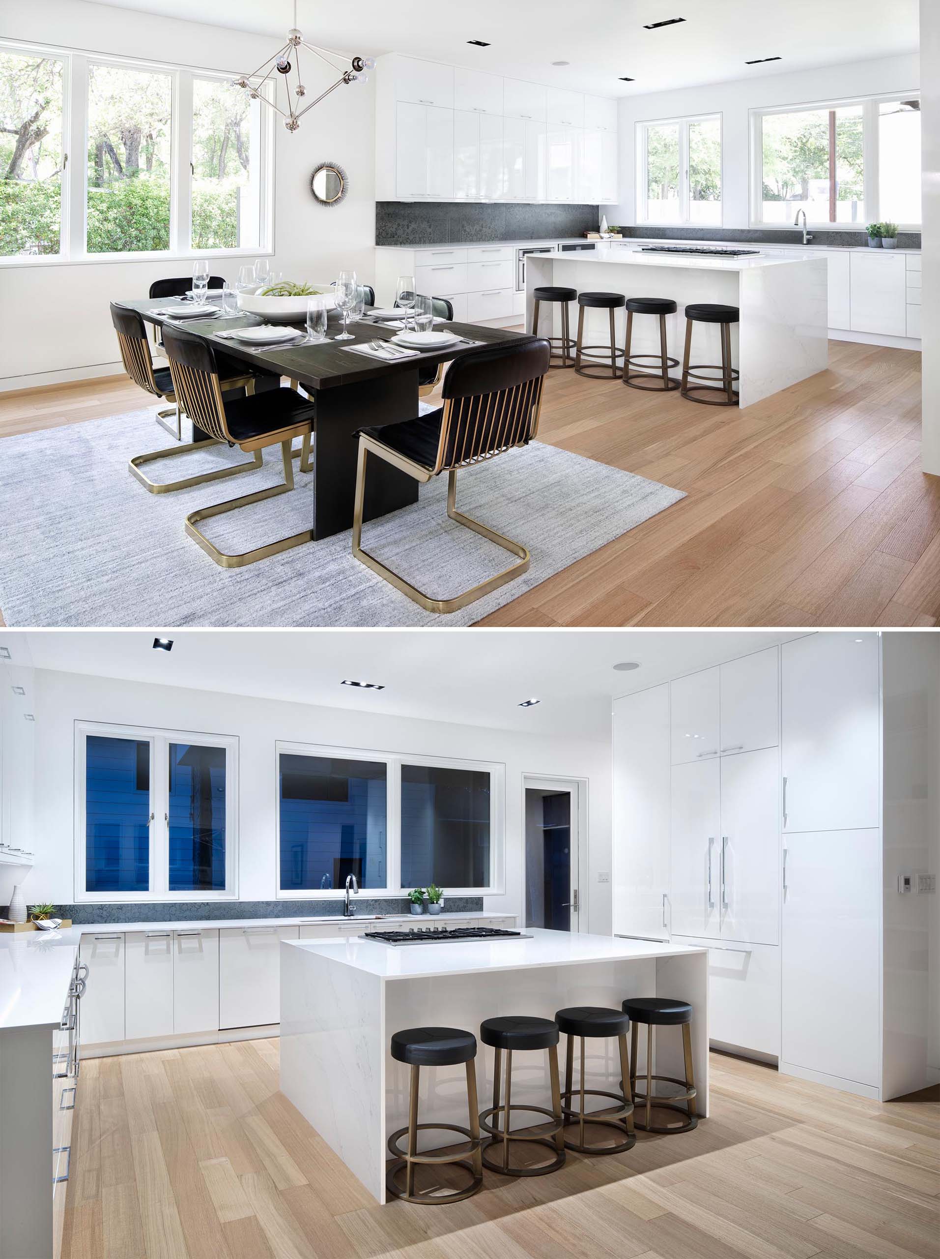 The dining area in this modern home is defined due to the placement of the rug on the wood floor, while the kitchen has modern white cabinets, a contrasting backsplash, and a central island with room for seating. 