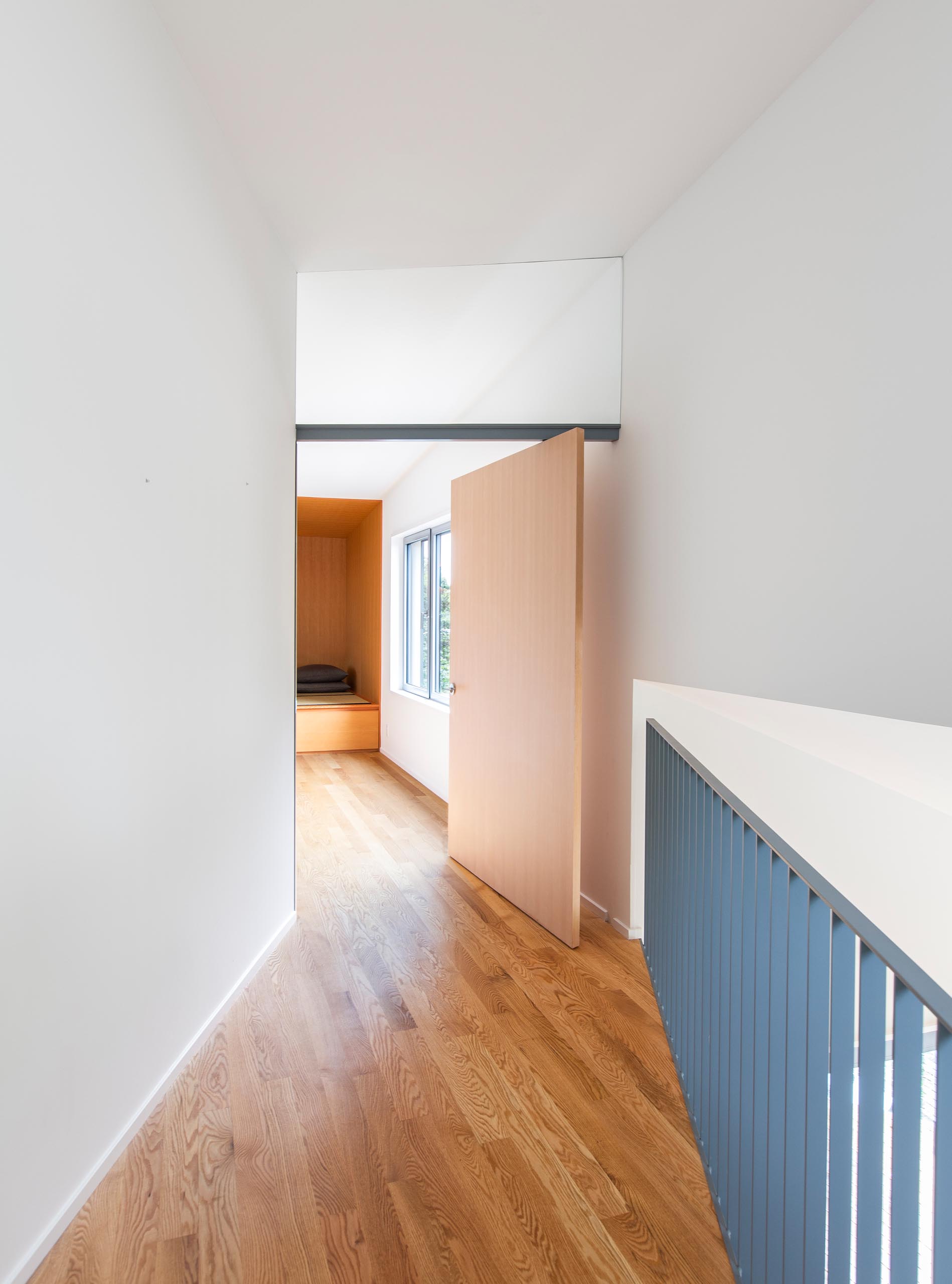 A modern home with red oak flooring and a pivoting bedroom door.