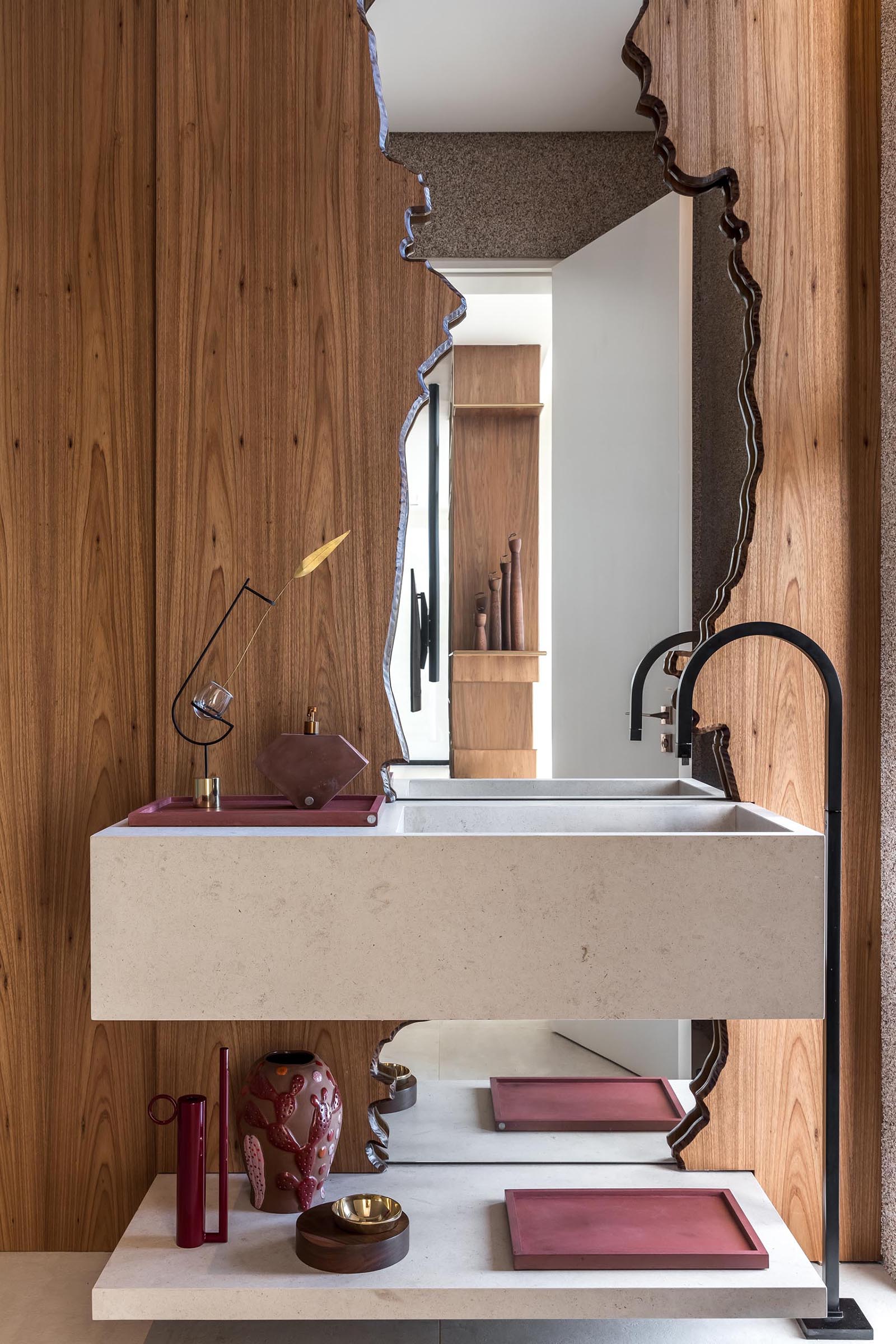 In a powder room, there's a mirror framed by floor-to-ceiling wood.