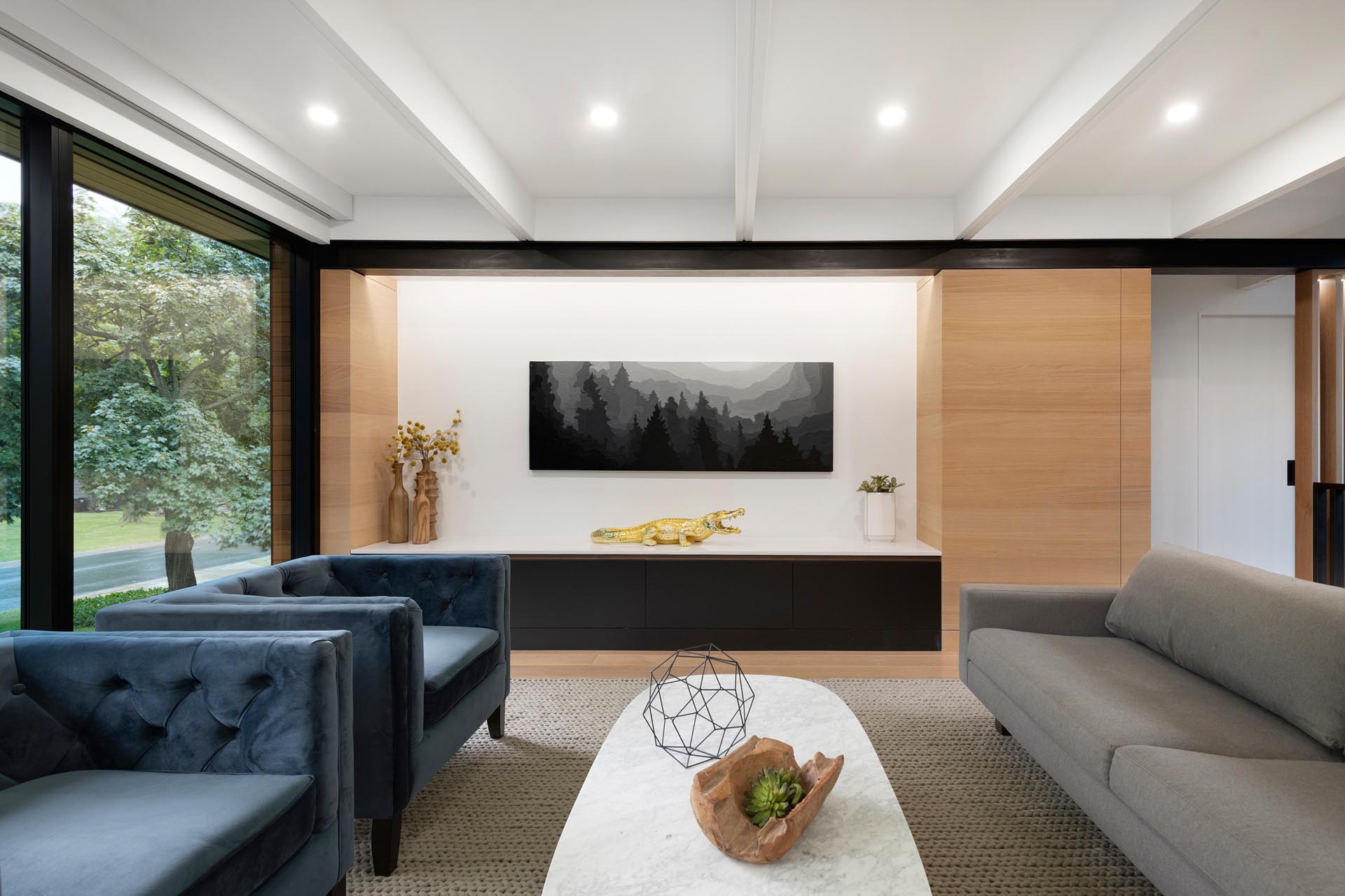 A formal living room with a sofa and pair of armchairs. Floor to ceiling windows add an abundance of natural light.