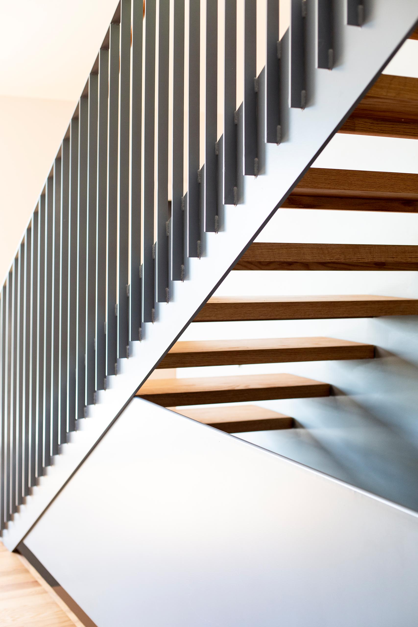 Matte gray and wood stairs connect the main level of this modern home with the upper floor.