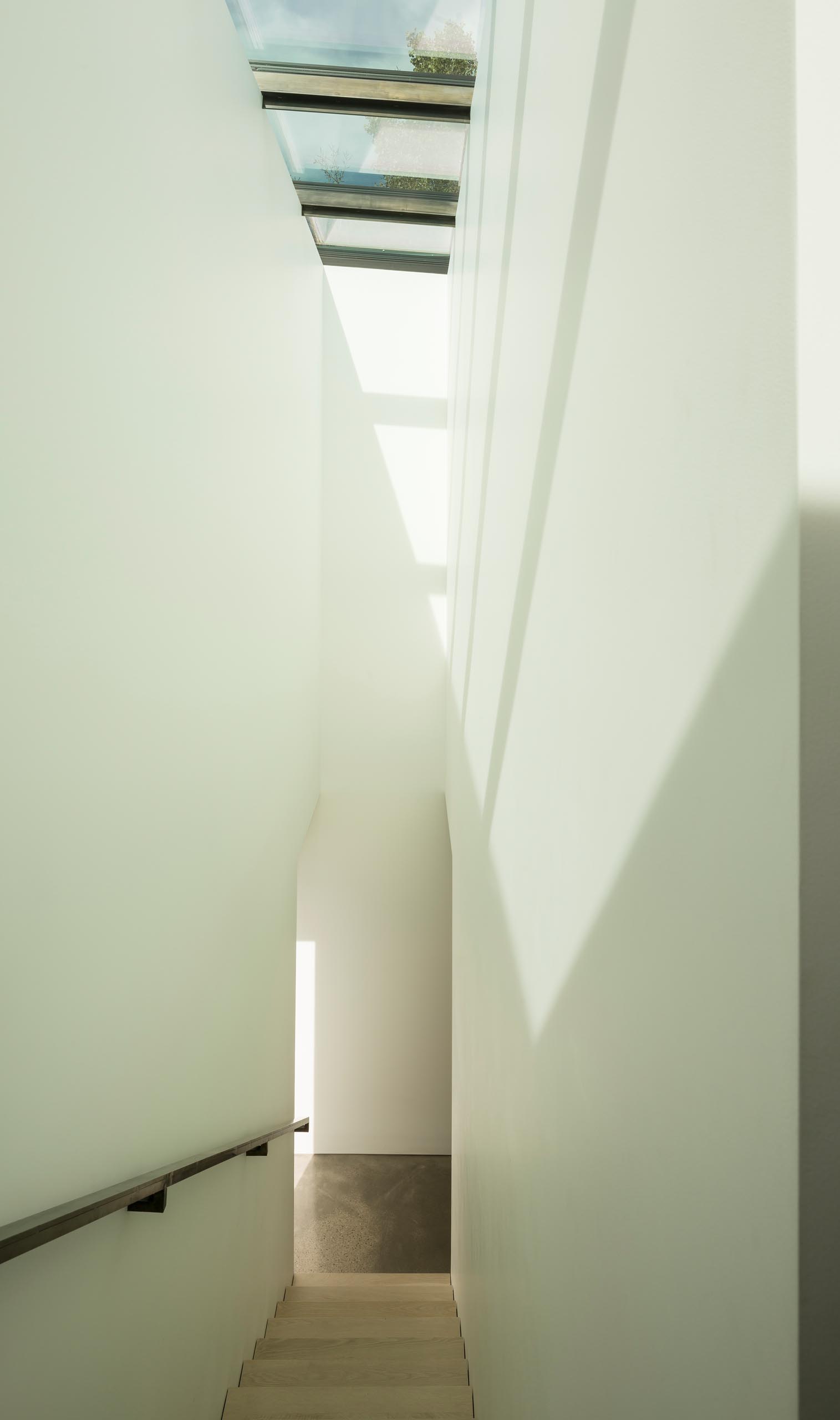 A modern staircase with metal handrail and skylights.