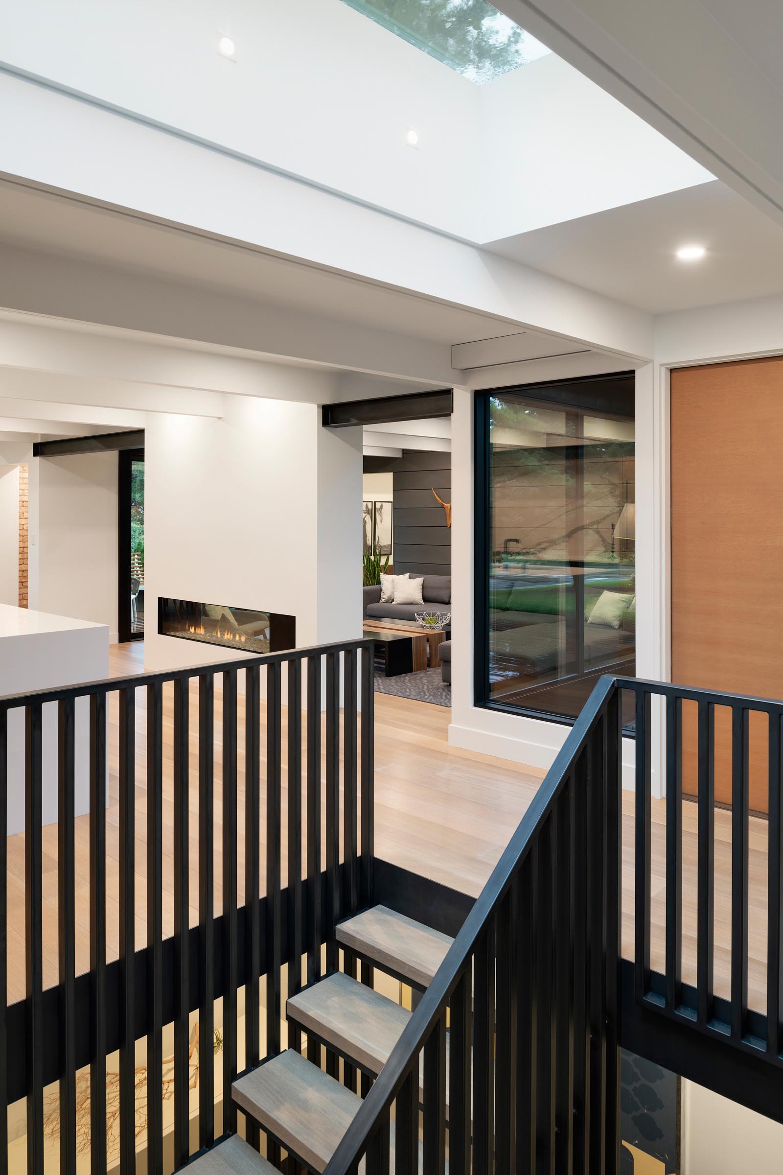 A skylight by the front door filters natural light through to the staircase that leads to the lower level of the home and features black handrails.