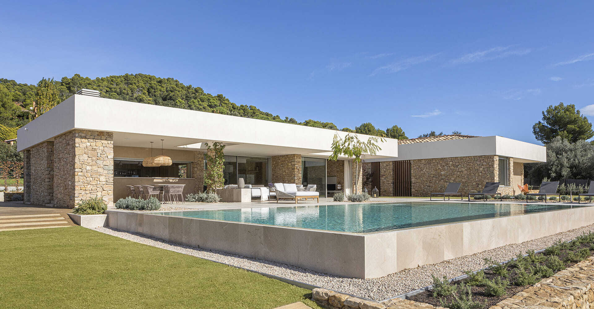 A modern house with stone walls that are highlighted by the use of both exterior and hidden lighting.