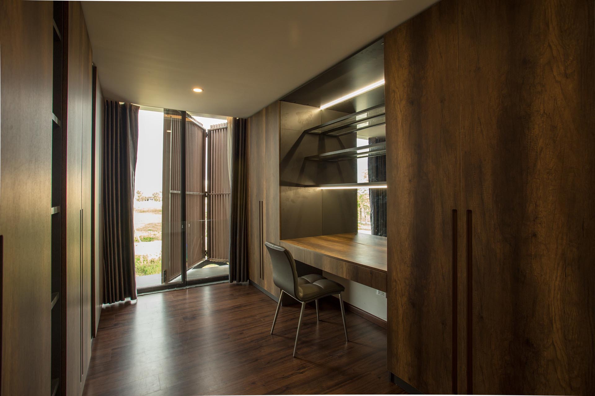 A walk-in closet with dark wood cabinets and a dedicated desk/vanity area.