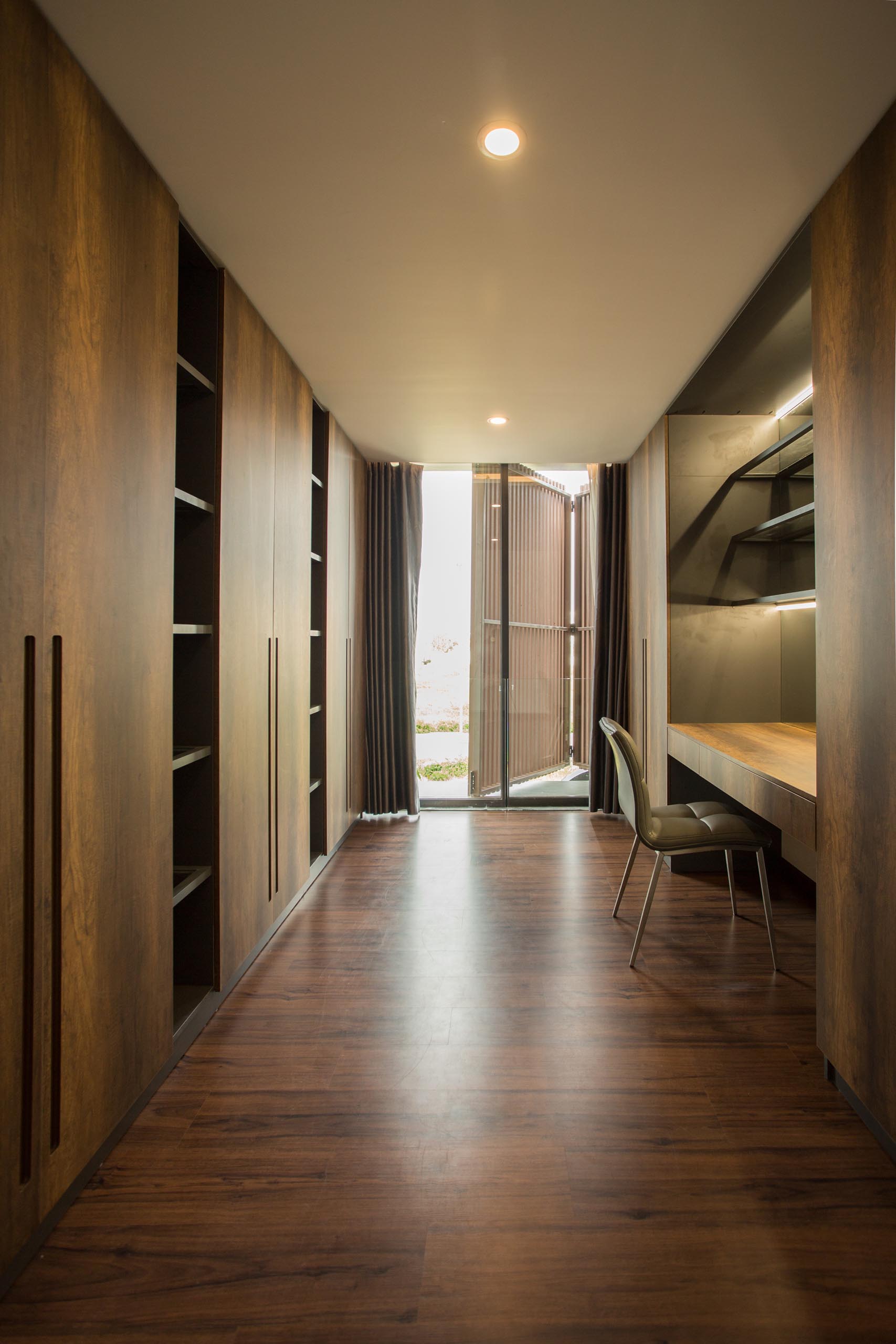 A walk-in closet with dark wood cabinets and a dedicated desk/vanity area.